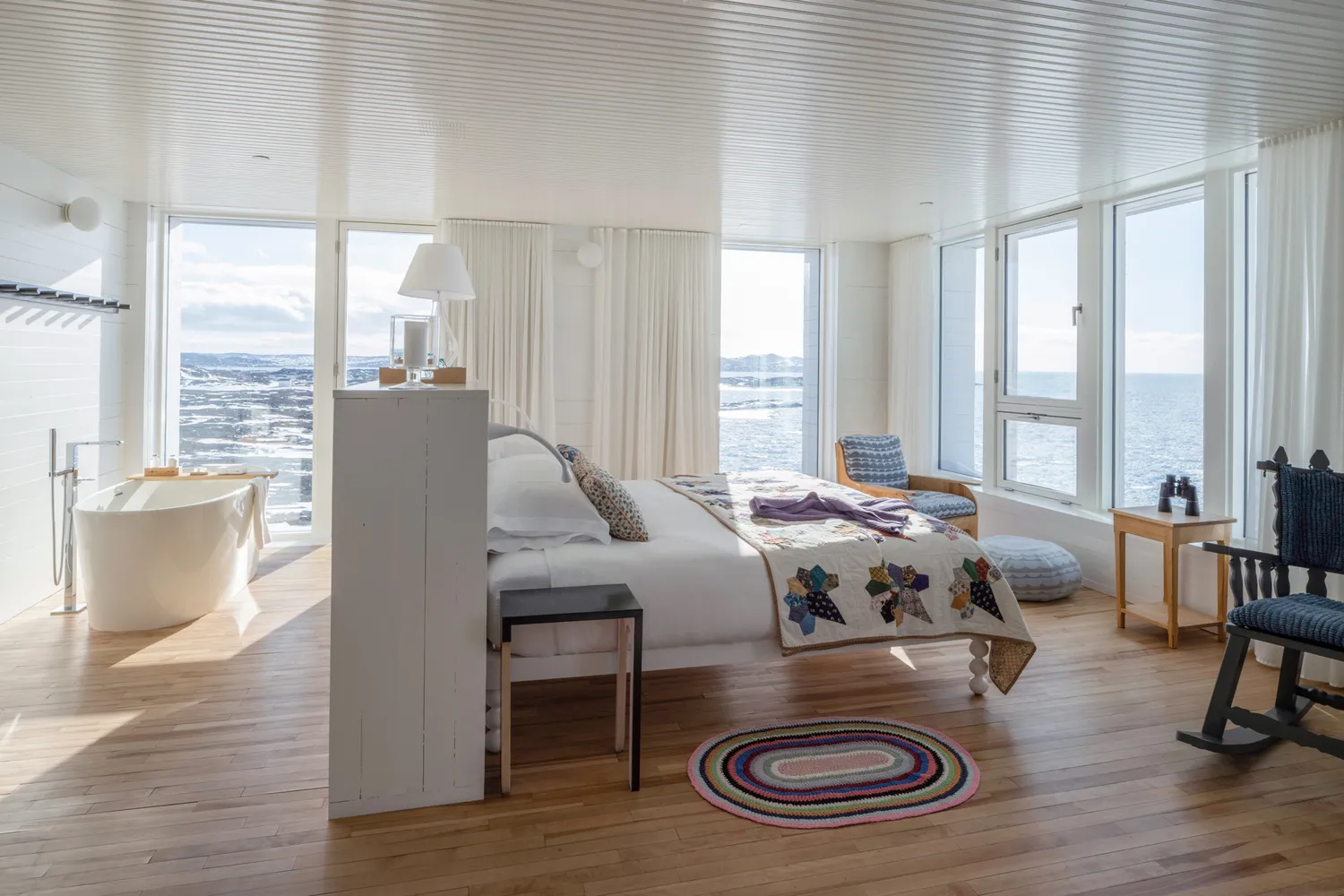 Interior of a Fogo Island Inn guest room with floor-to-ceiling windows overlooking the cold blue North Atlantic.