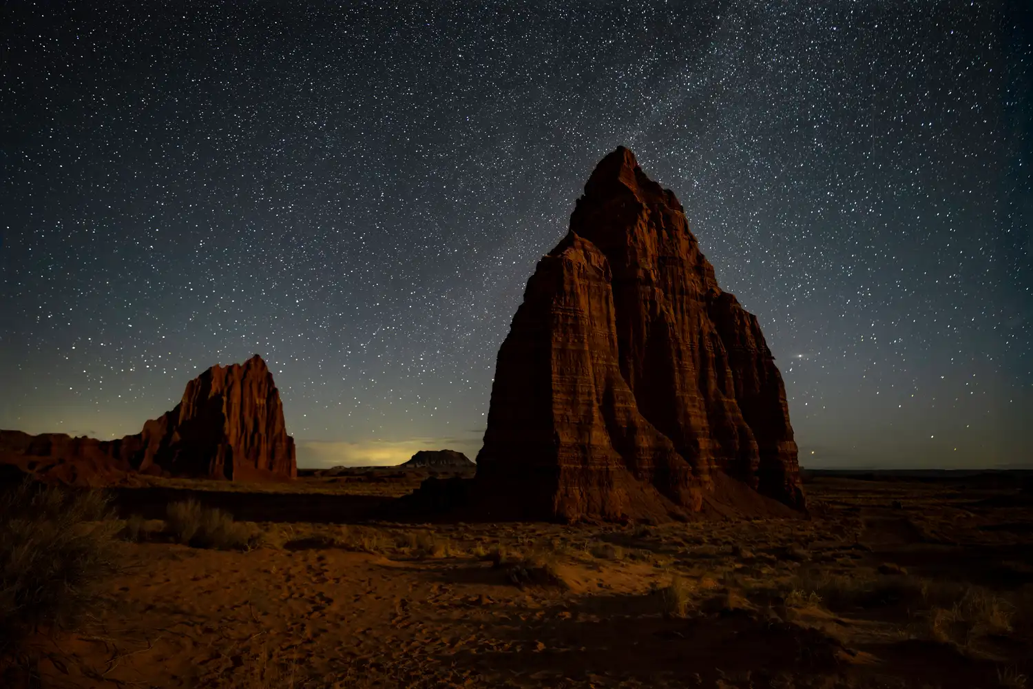Desert rock formations known as the Temple of the Sun under a dense field of stars at night.