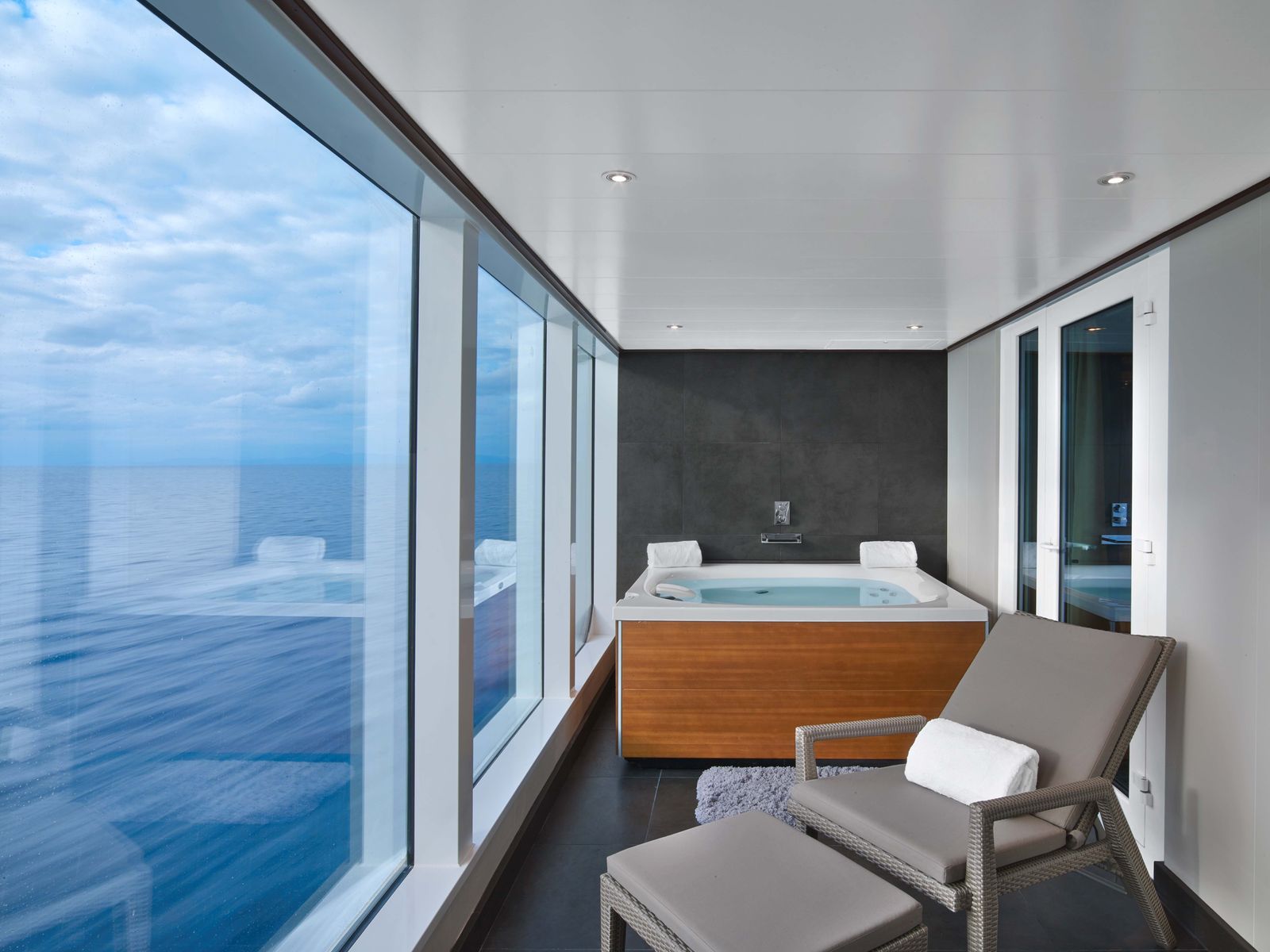 A private outdoor bathtub on a luxury cruise ship balcony overlooking the ocean.