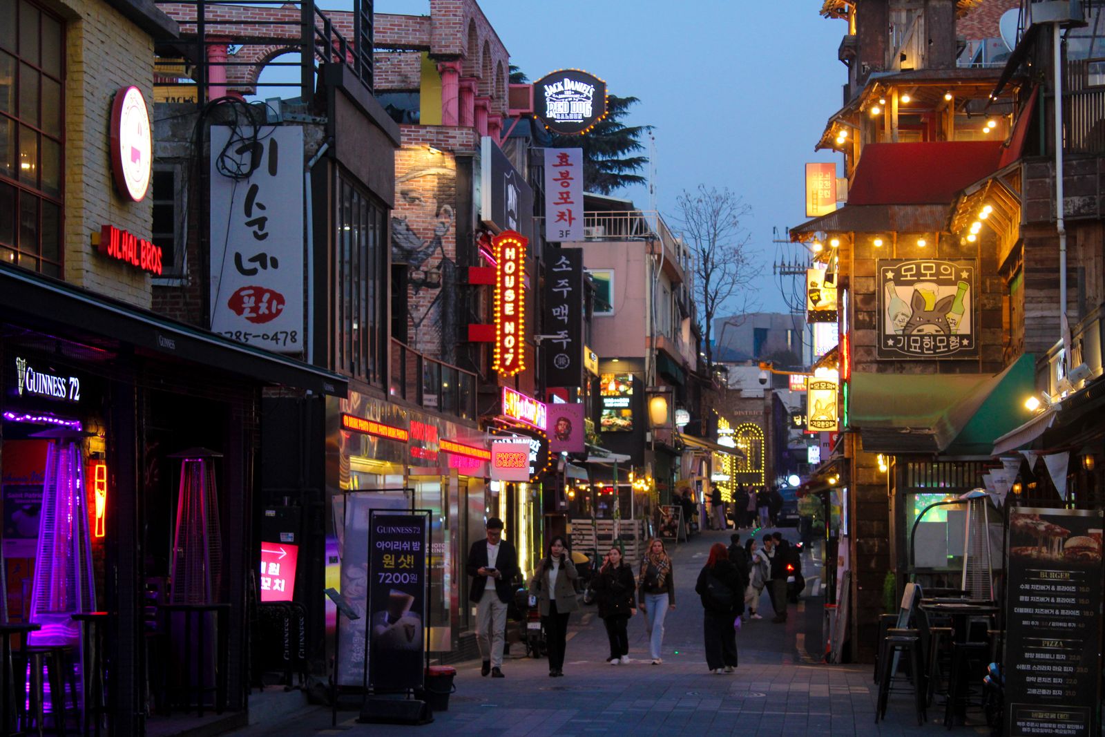 An intimate narrow walking alley in a Seoul neighborhood at night with soft lighting.