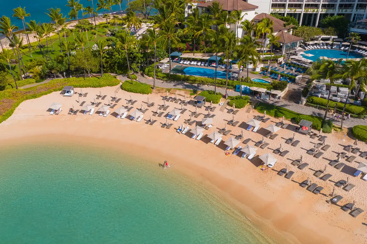 Aerial view of the private beachfront at Ko Olina with sun loungers and crystal clear lagoon water.