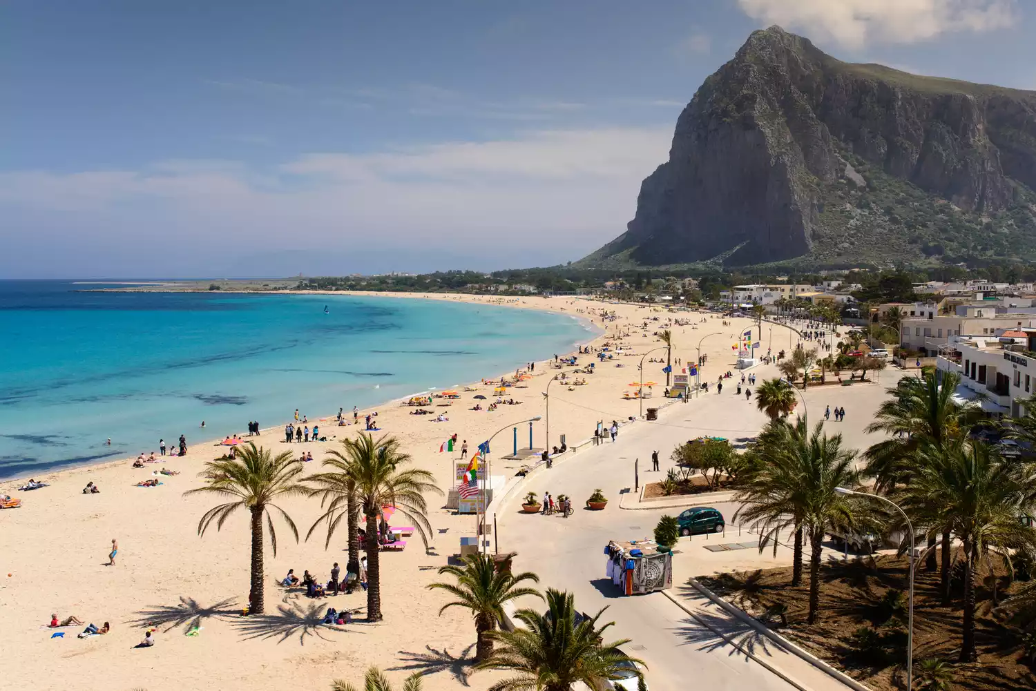 A wide, white sandy beach with turquoise water in the town of San Vito Lo Capo, Sicily.