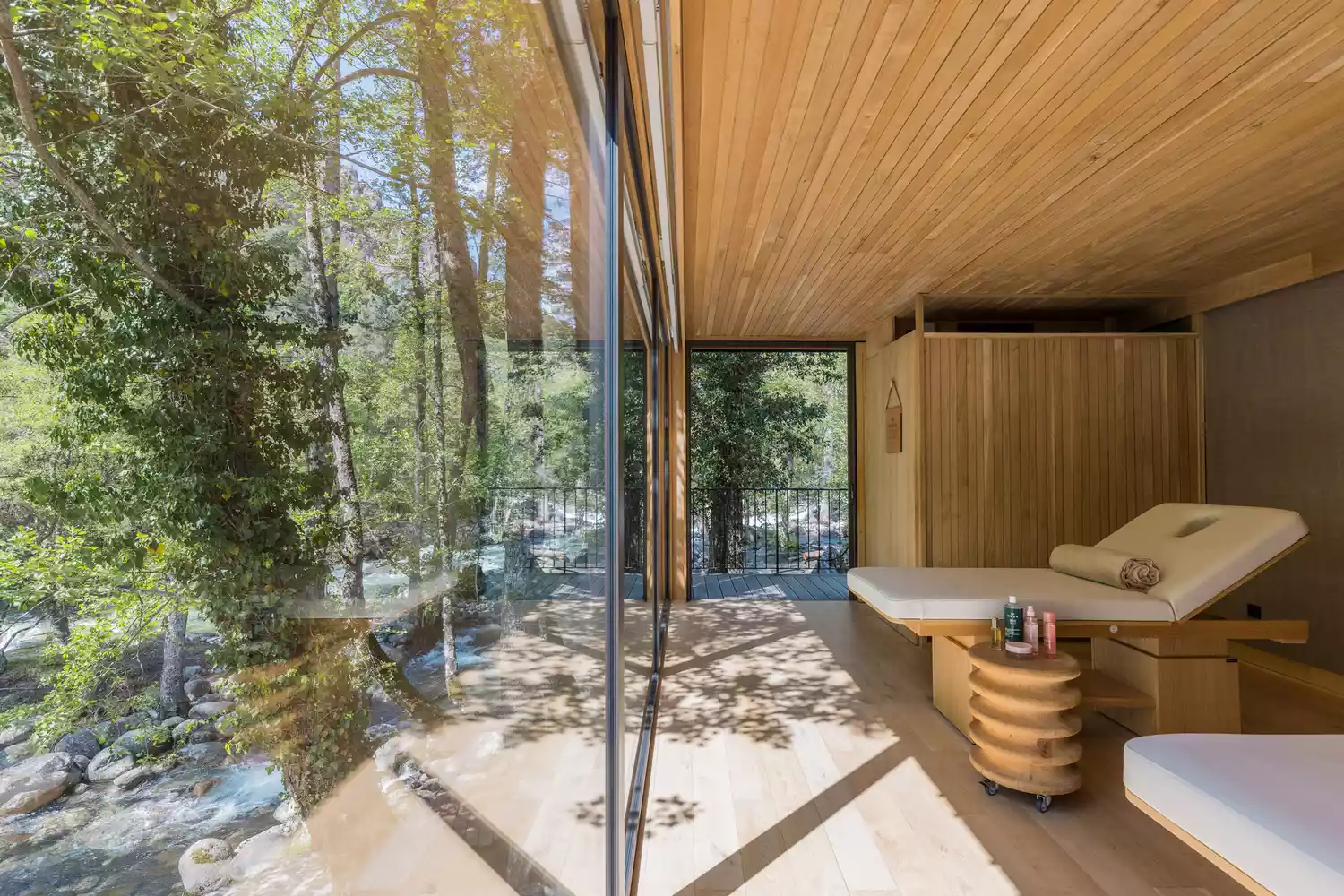 An indoor spa area with large glass windows looking out onto a dense, green forest.