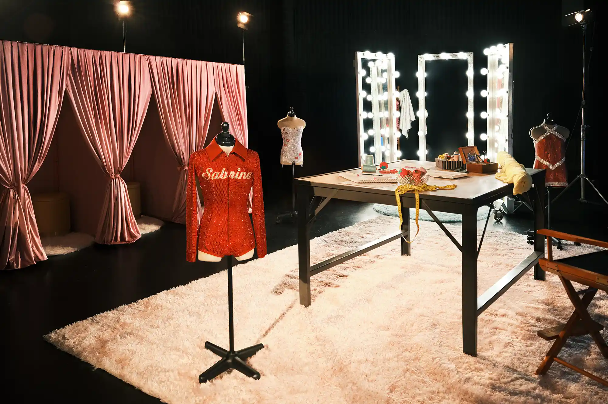 A professional makeup and dressing room featuring lighted mirrors and velvet curtains.