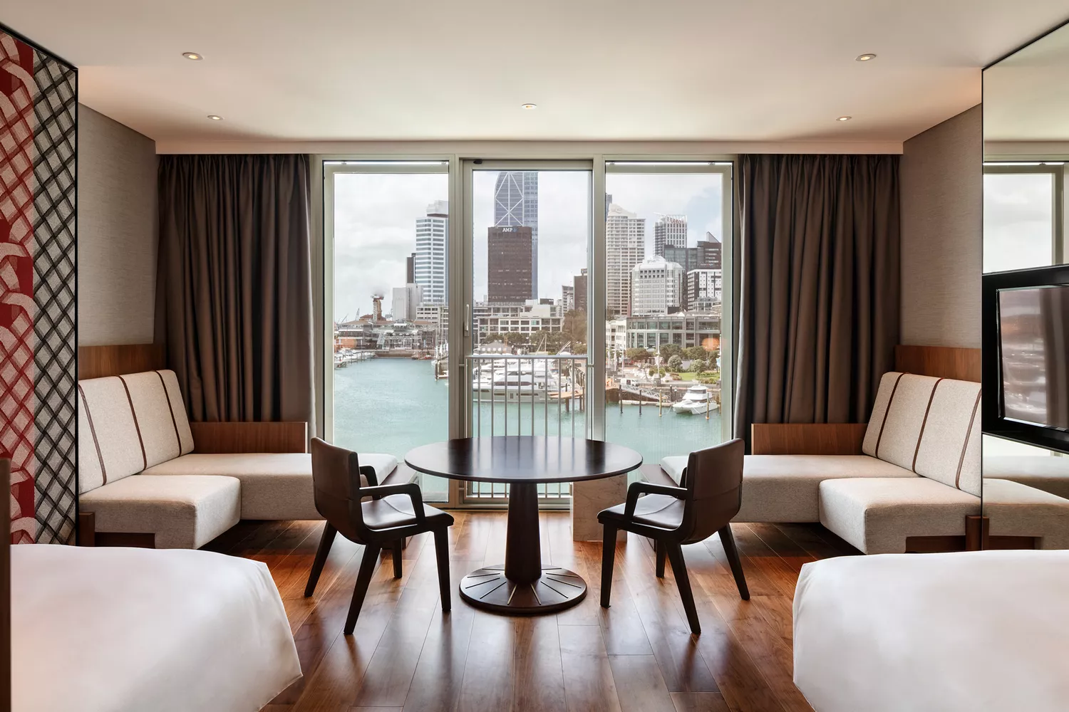 A luxury hotel suite featuring floor-to-ceiling windows overlooking Auckland's harbor