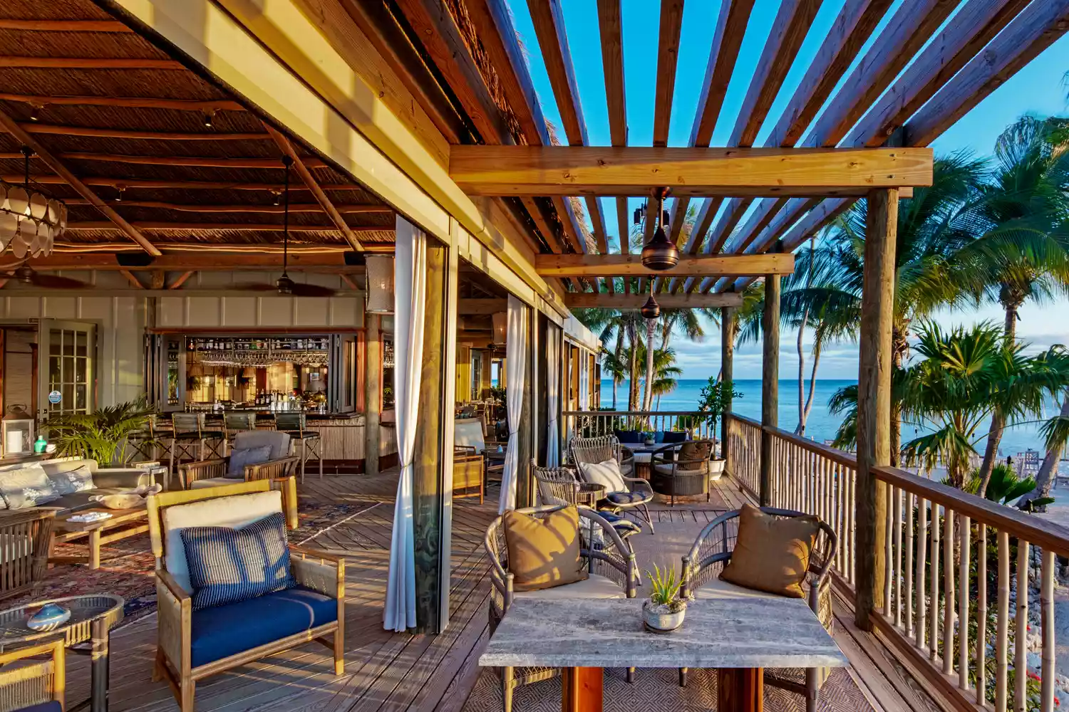 Interior view of a luxury suite at Little Palm Island featuring high vaulted ceilings, teak wood furniture, and tropical elegance.