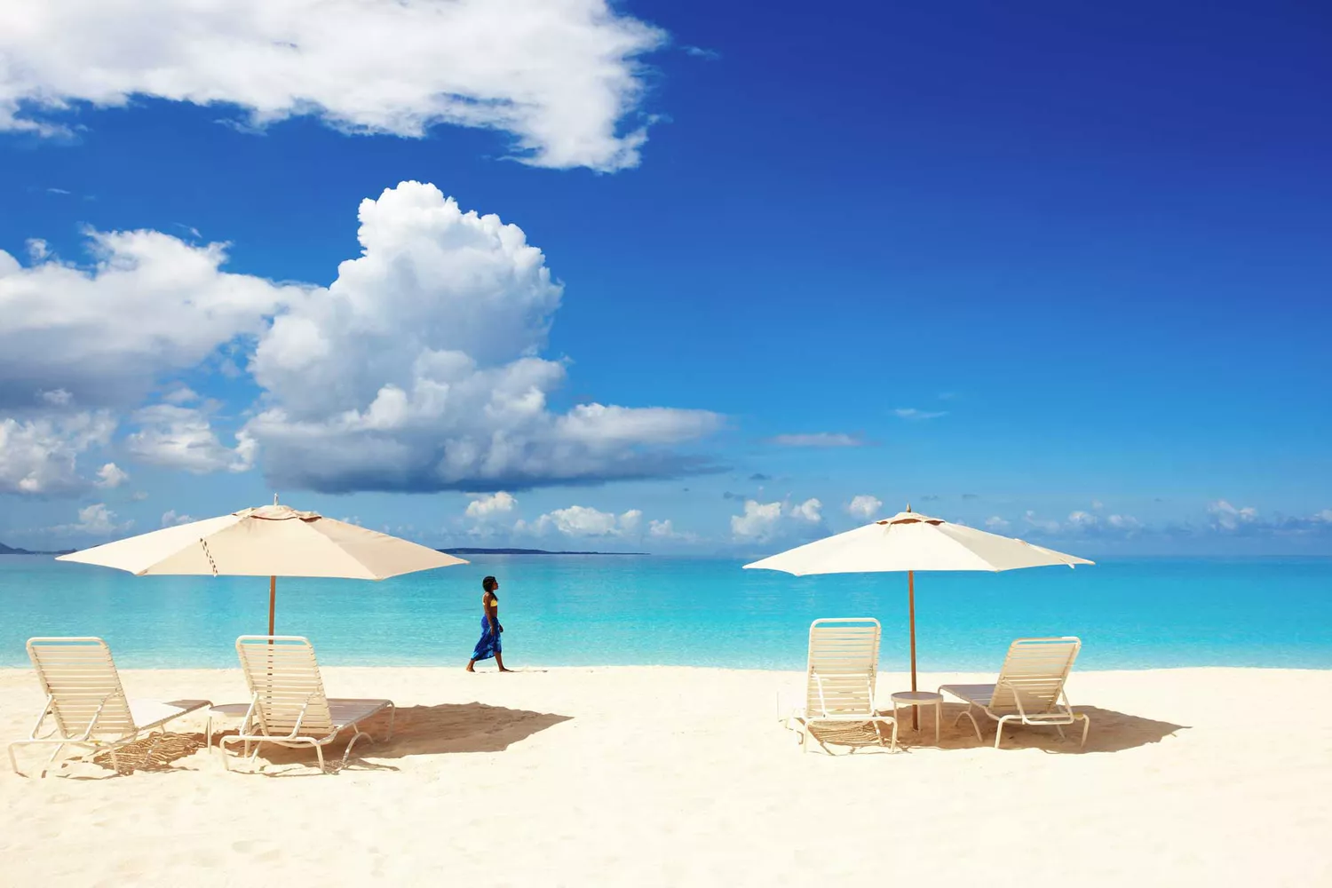 Beach umbrellas on a pristine white sand beach in Anguilla with turquoise water in the background.