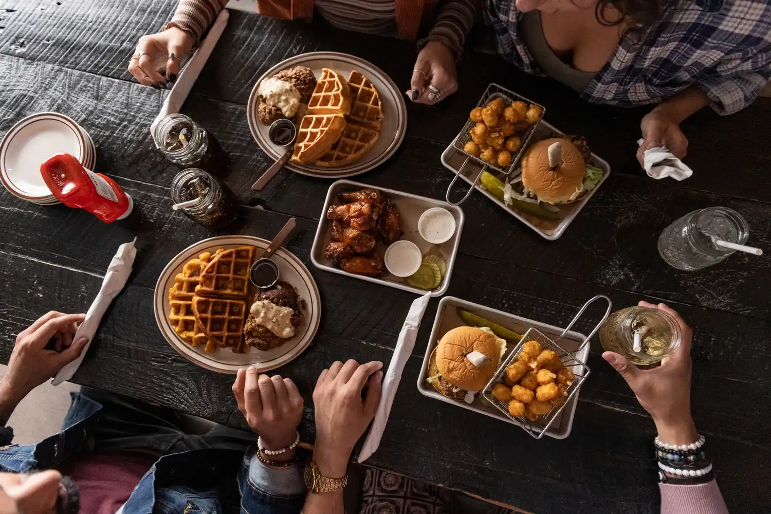 A tabletop view of a shared meal featuring burgers, waffles, and fries at a local Winston-Salem restaurant.