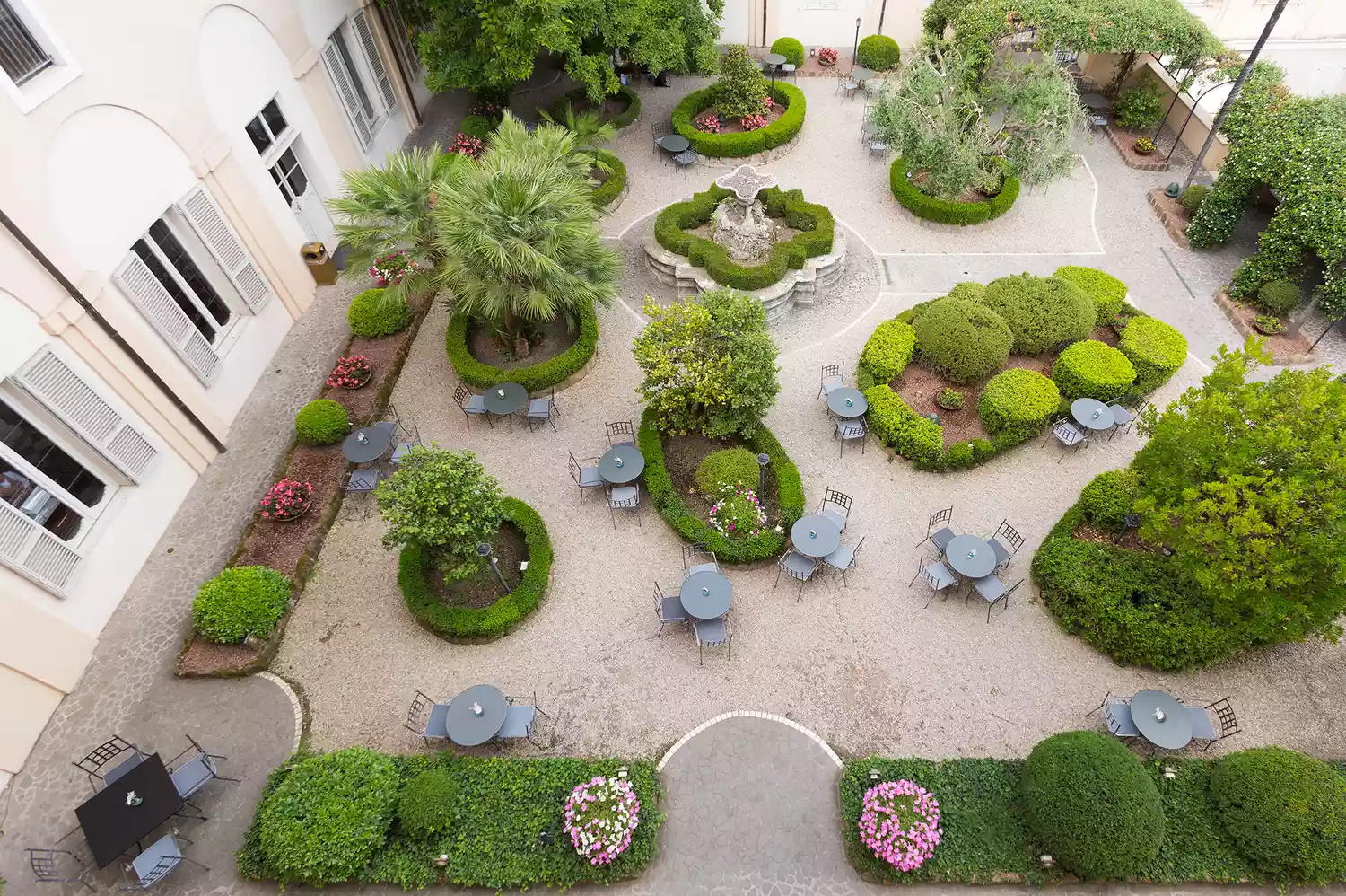 An overhead view of the lush, green courtyard garden and symmetric hallways at Donna Camilla Savelli.