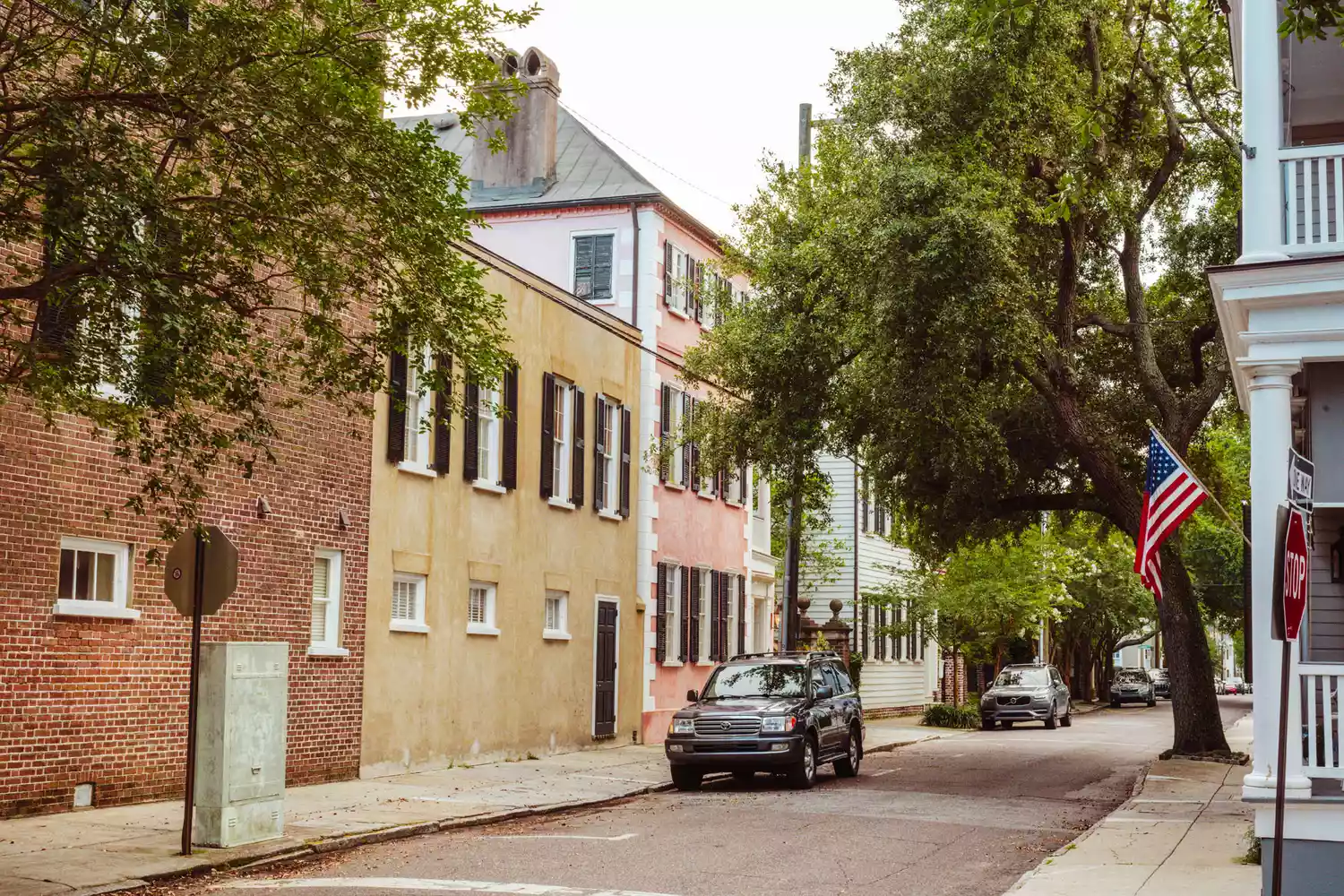 A row of historic colorful houses along a street in Charleston.
