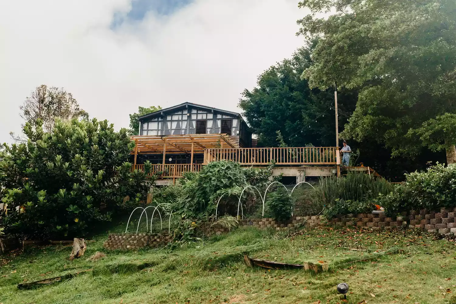 The main wooden farm building at El Pretexto featuring an outdoor wooden deck and surrounding greenery.