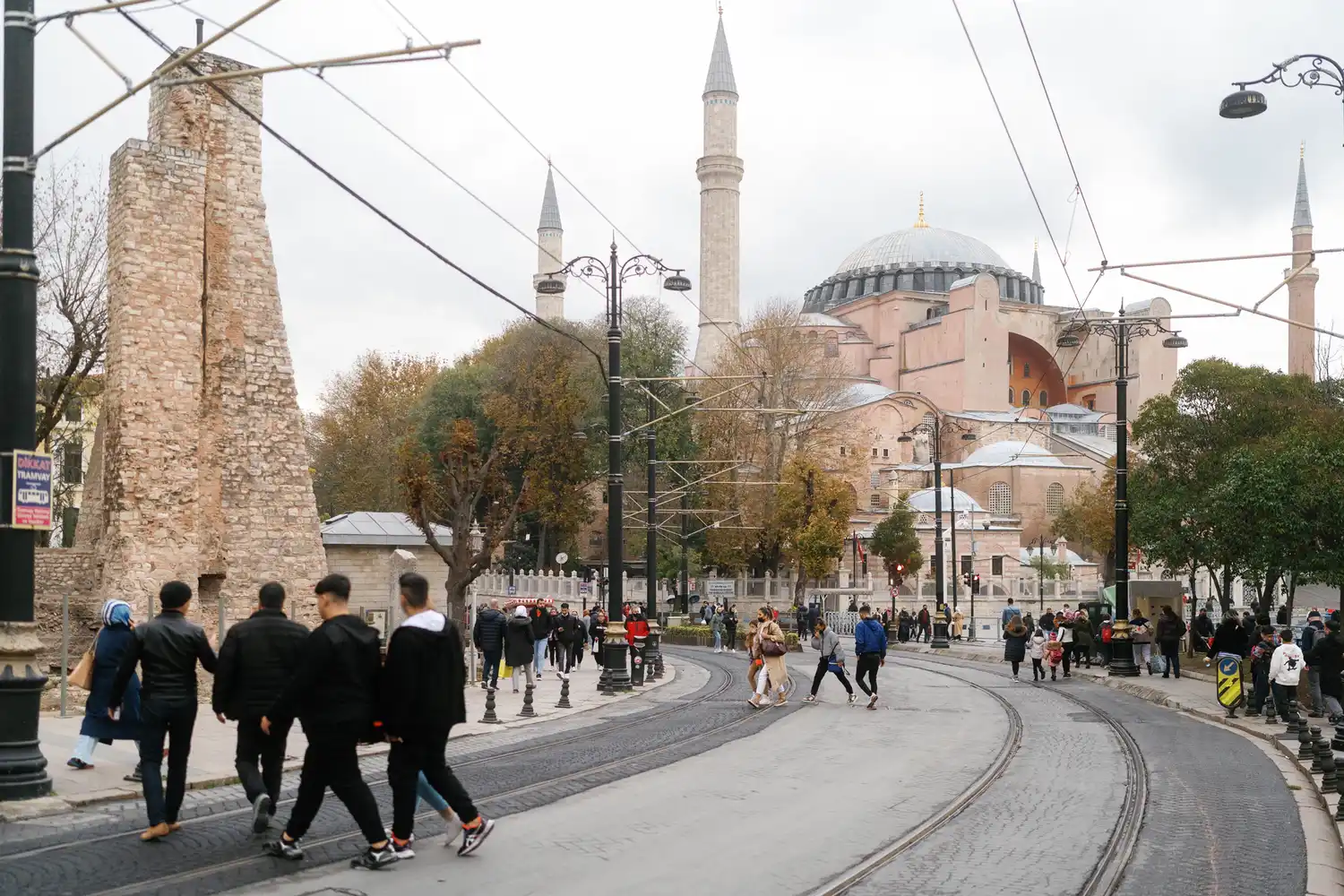 Pedestrians walking on a cobblestone street in Sultanahmet with the Hagia Sophia in the background.