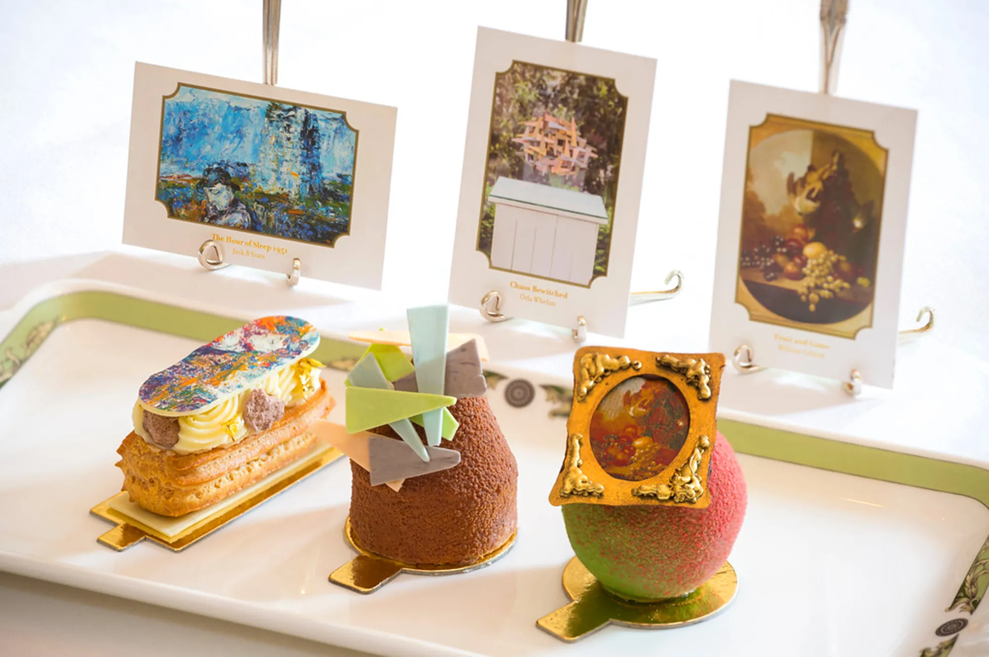 A selection of colorful art-inspired pastries and desserts served on a tray with reference art cards.