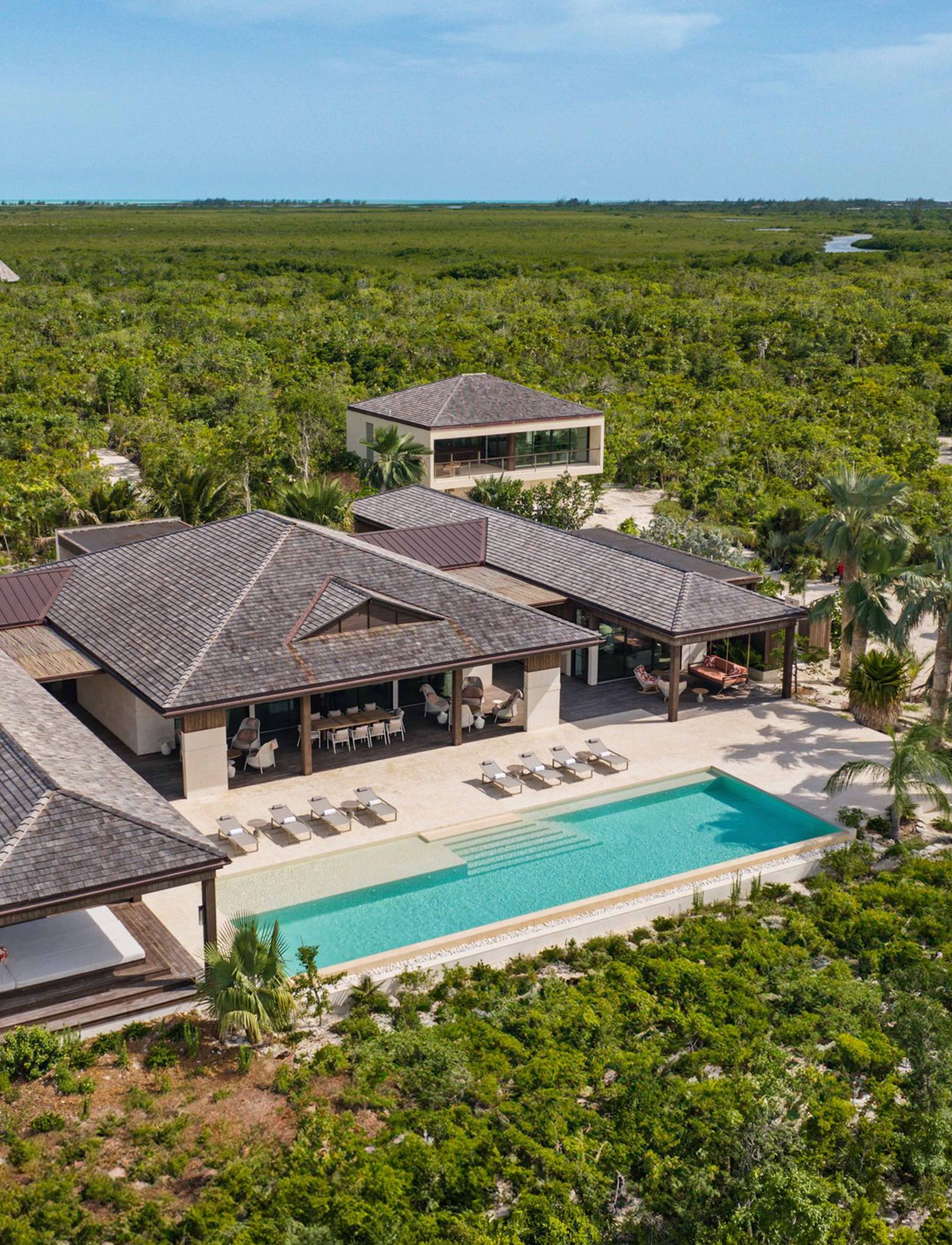 An aerial perspective of a luxury resort swimming pool surrounded by tropical architecture.