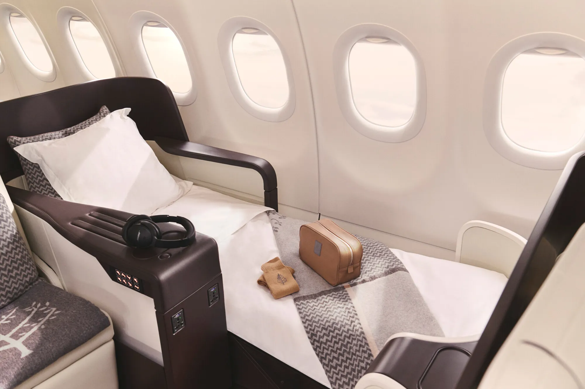 Interior of a private jet showing a luxury leather seat in a fully reclined position with premium bedding.