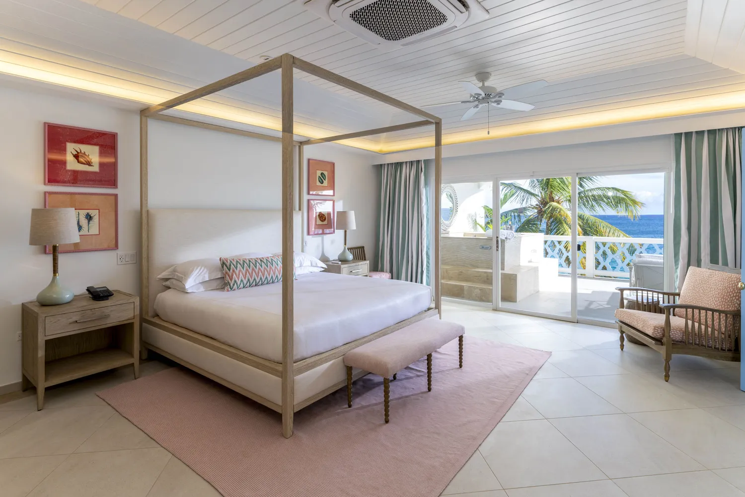 A luxury hotel room at Curtain Bluff featuring a white canopy bed and a balcony with an ocean view.