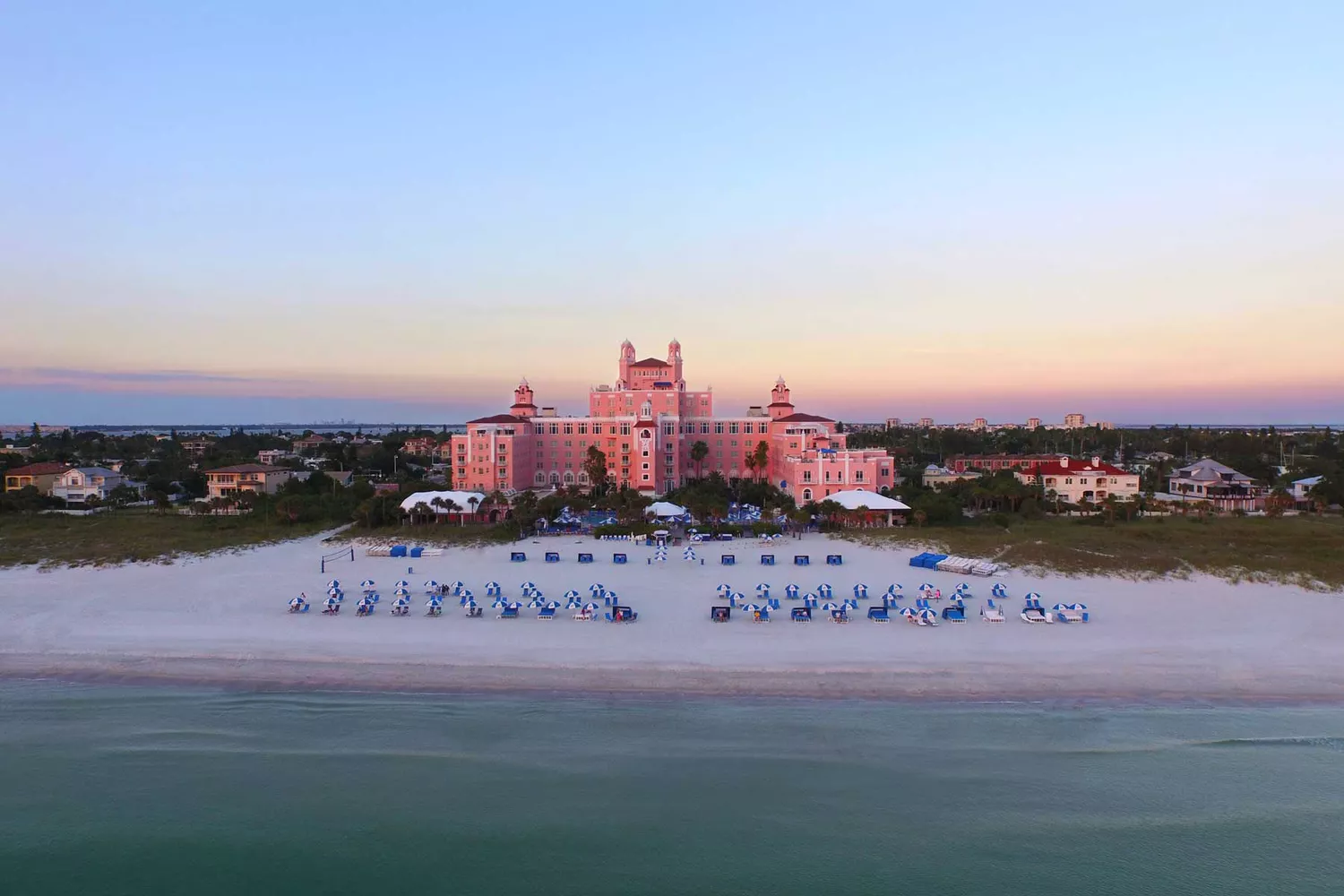 The historic pink exterior of the Don CeSar hotel overlooking the beach at sunset.