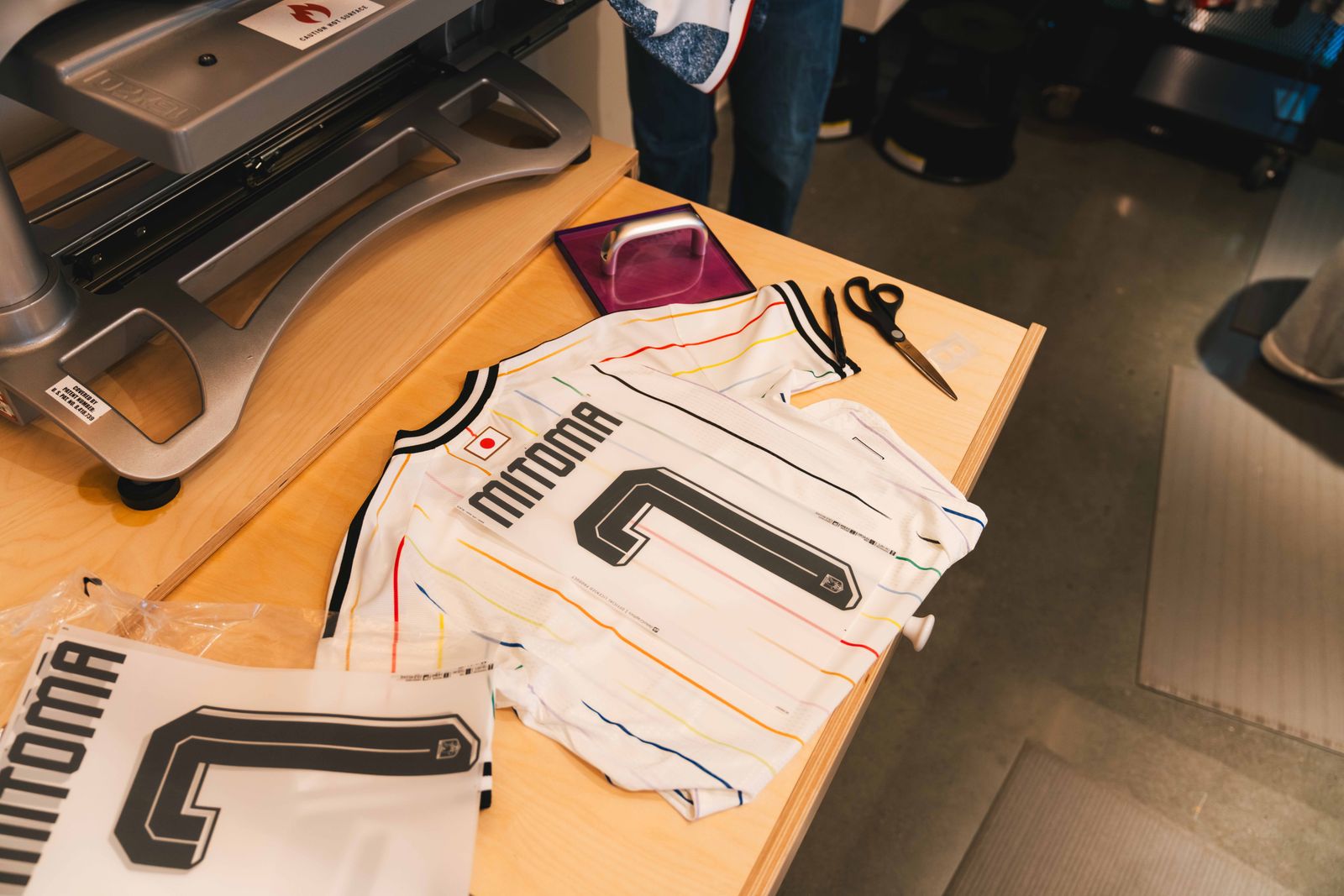 A person working on a jersey with textile tools and symbols, focusing on custom football apparel.