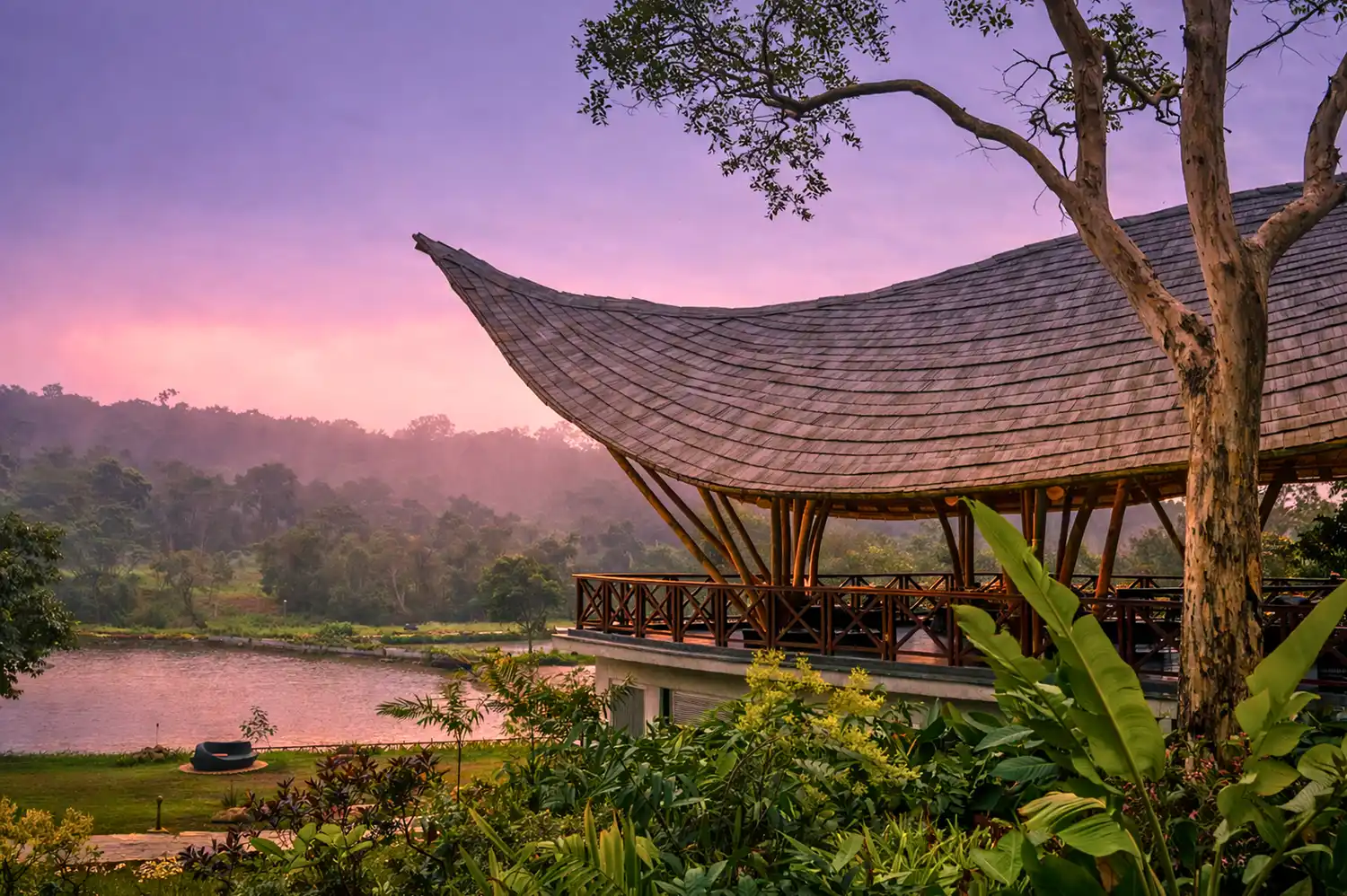 Contemporary building with a flowing curved roof design overlooking the forest and river at The Leela Coorg.