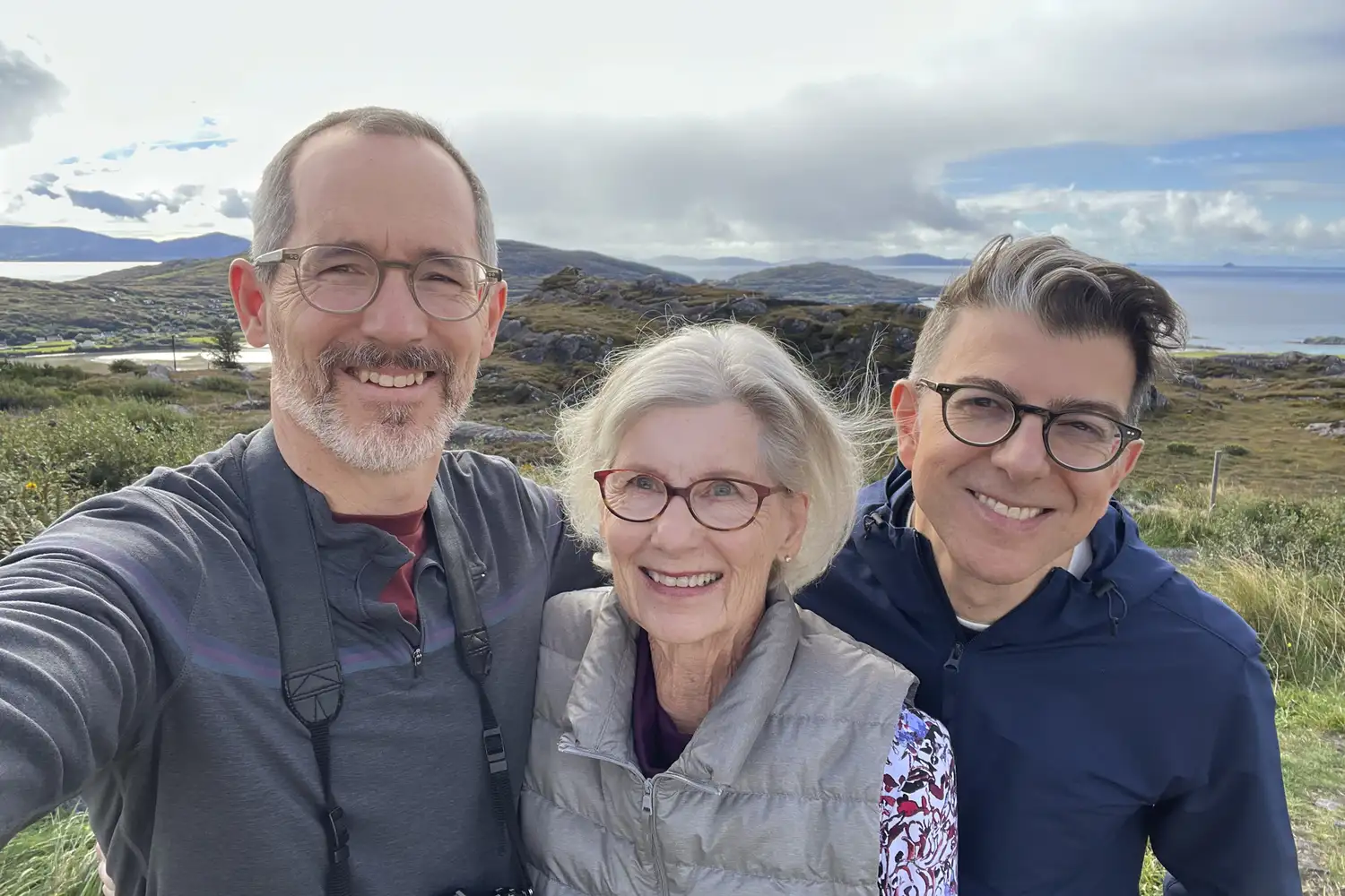 A smiling group of travelers taking a selfie against a backdrop of scenic Irish mountains.