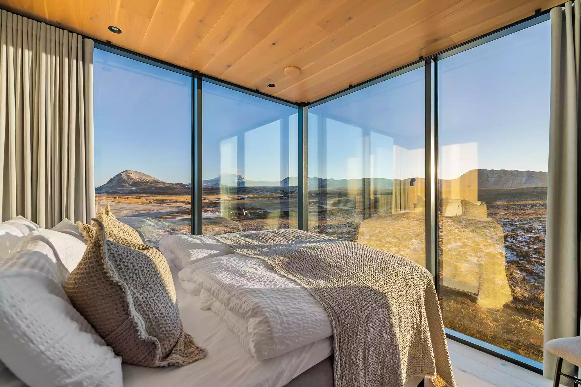 Modern minimalist bedroom inside an Iceland mirror hotel with panoramic views.