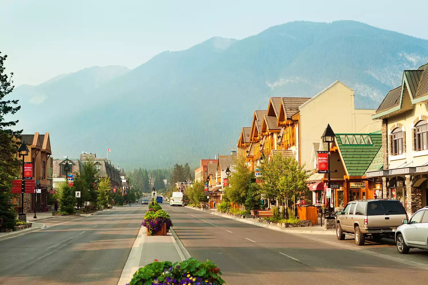 A busy street in the town of Banff with tourists and majestic mountain peaks in the background.