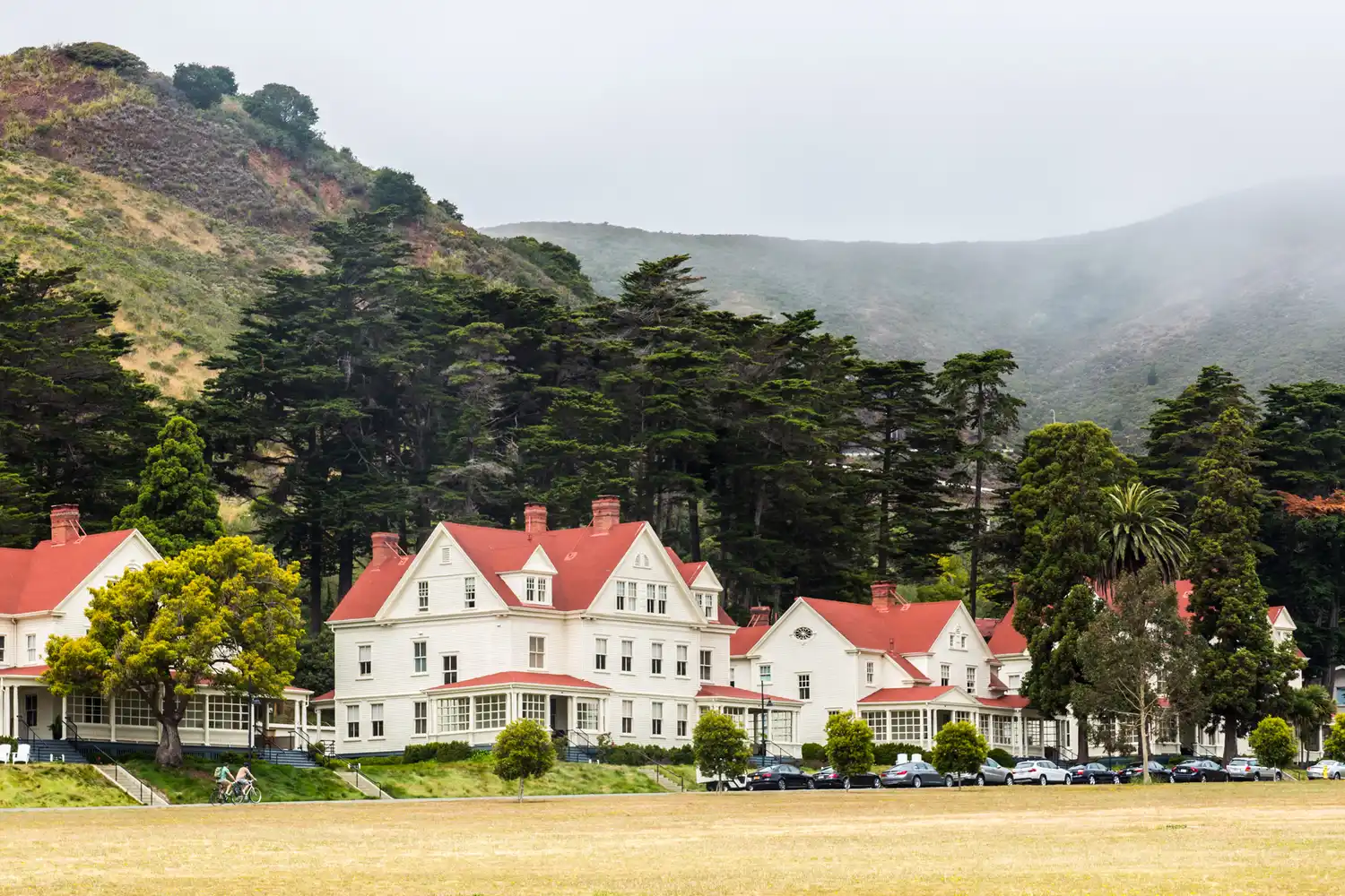 Exterior view of Cavallo Point in Sausalito featuring red-roofed buildings surrounded by lush greenery and hills.