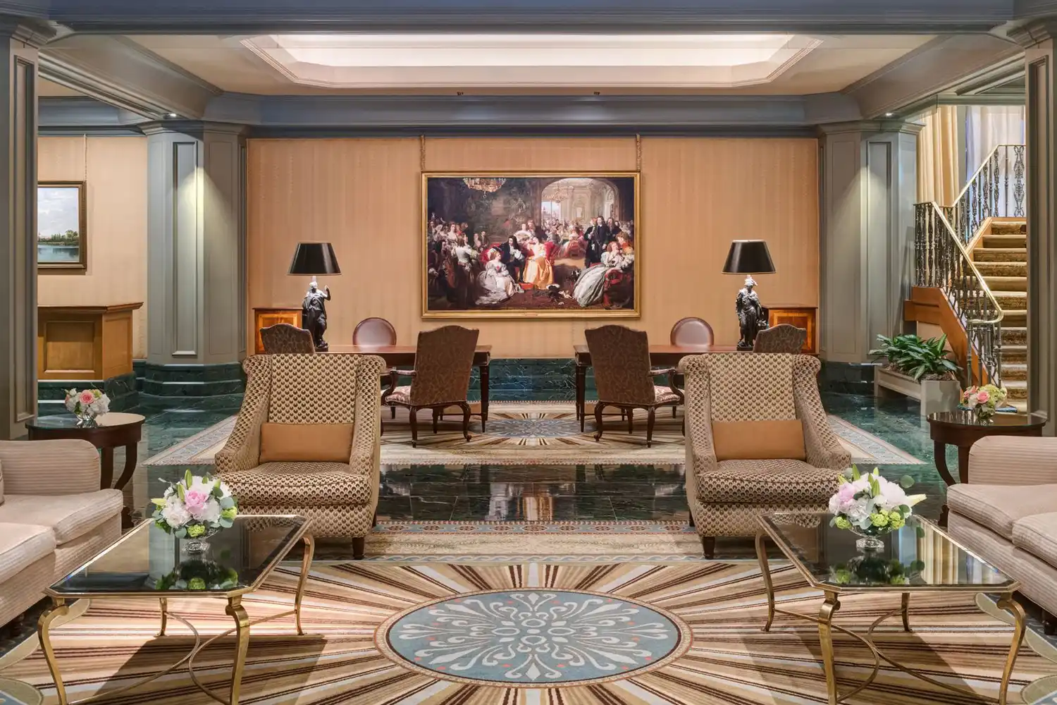 The grand lobby of The Windsor Court with classical furniture, art, and a staircase.