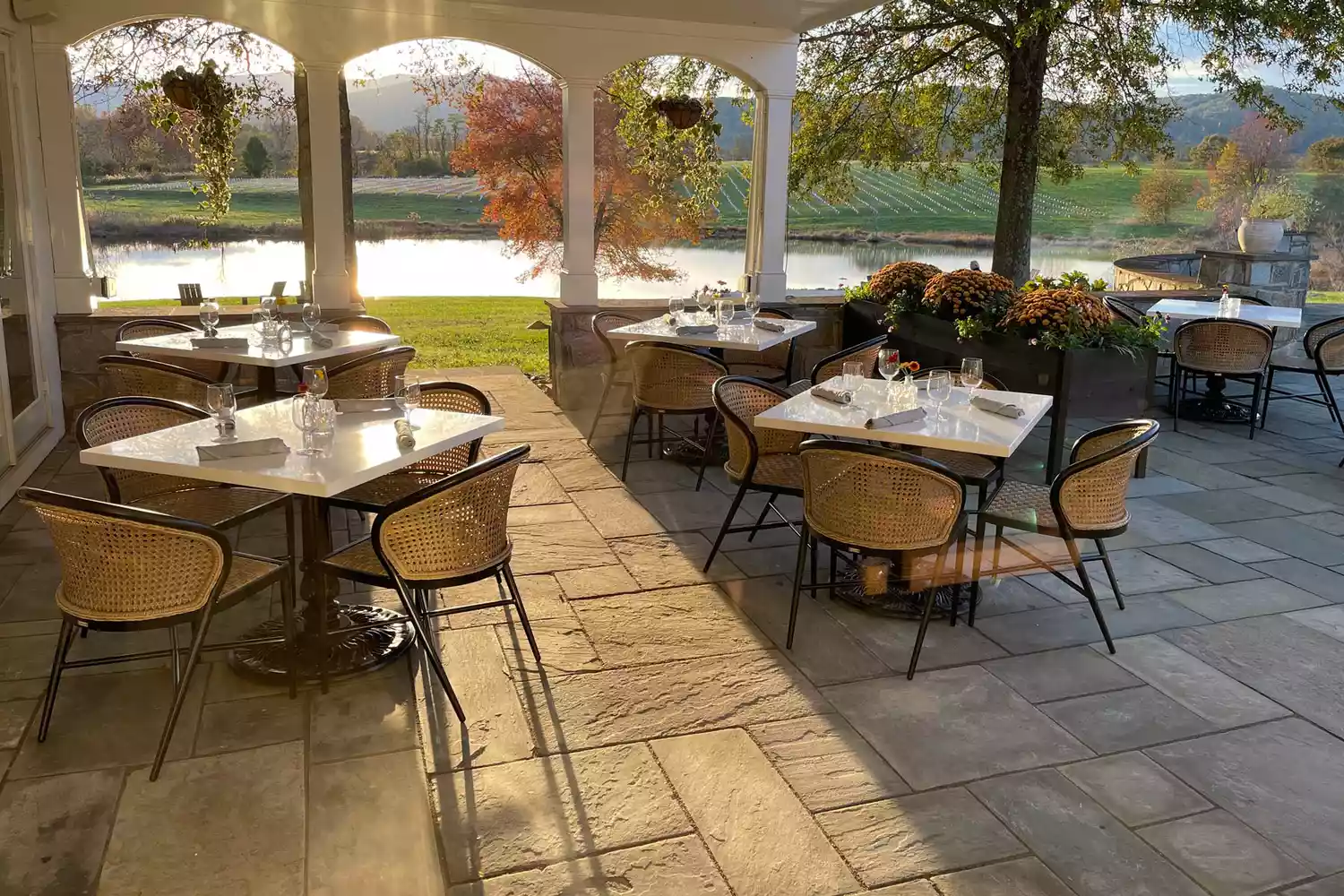 An outdoor dining patio at Blue Rock with tables set near a pond and mountain vistas.