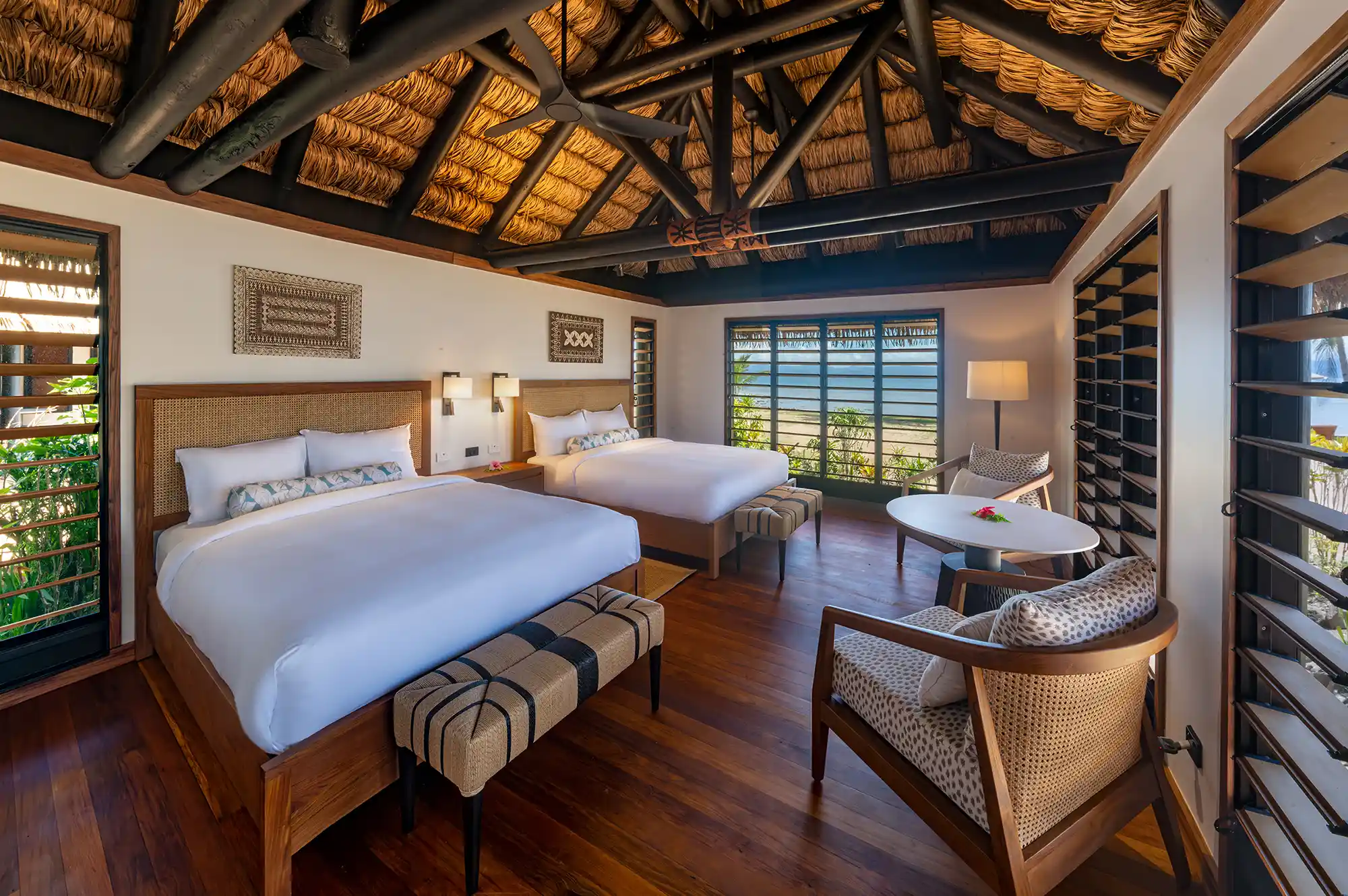 Interior of a luxury bedroom with traditional woven ceilings, wooden furniture, and garden views.