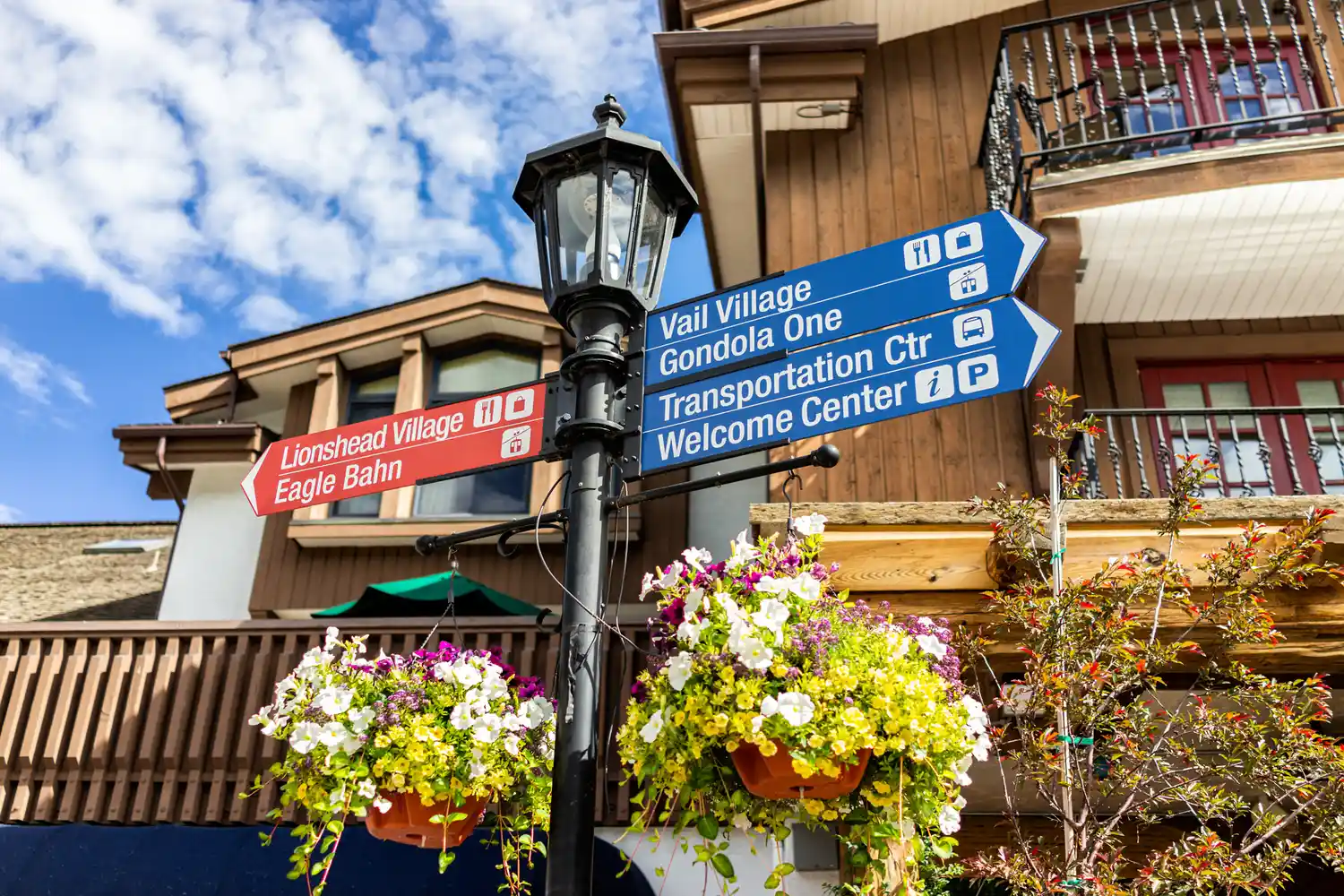 A wooden directional signpost in Vail pointing towards Lionshead and Vail Village.