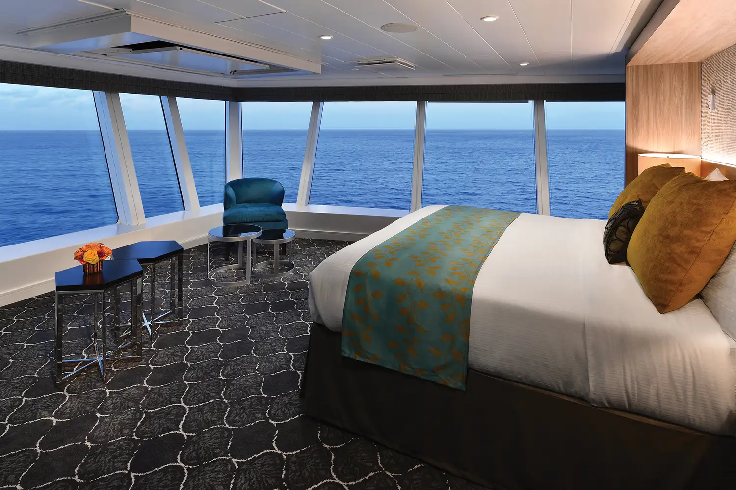 The interior of the Ultimate Panoramic Suite featuring a large bed and floor-to-ceiling windows with ocean views.