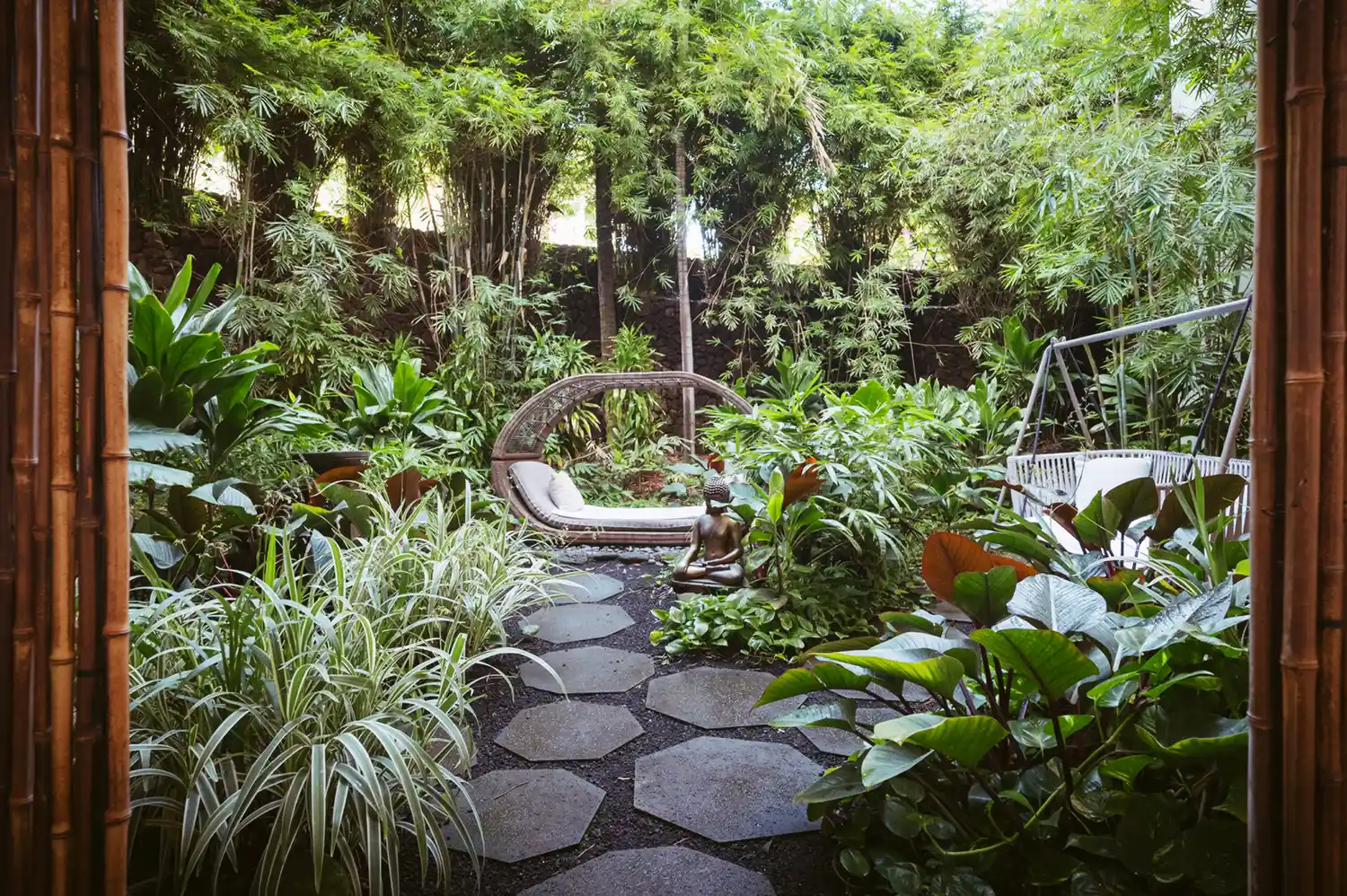 Lush outdoor garden at the Naupaka Spa featuring tropical plants and a curved stone seat.