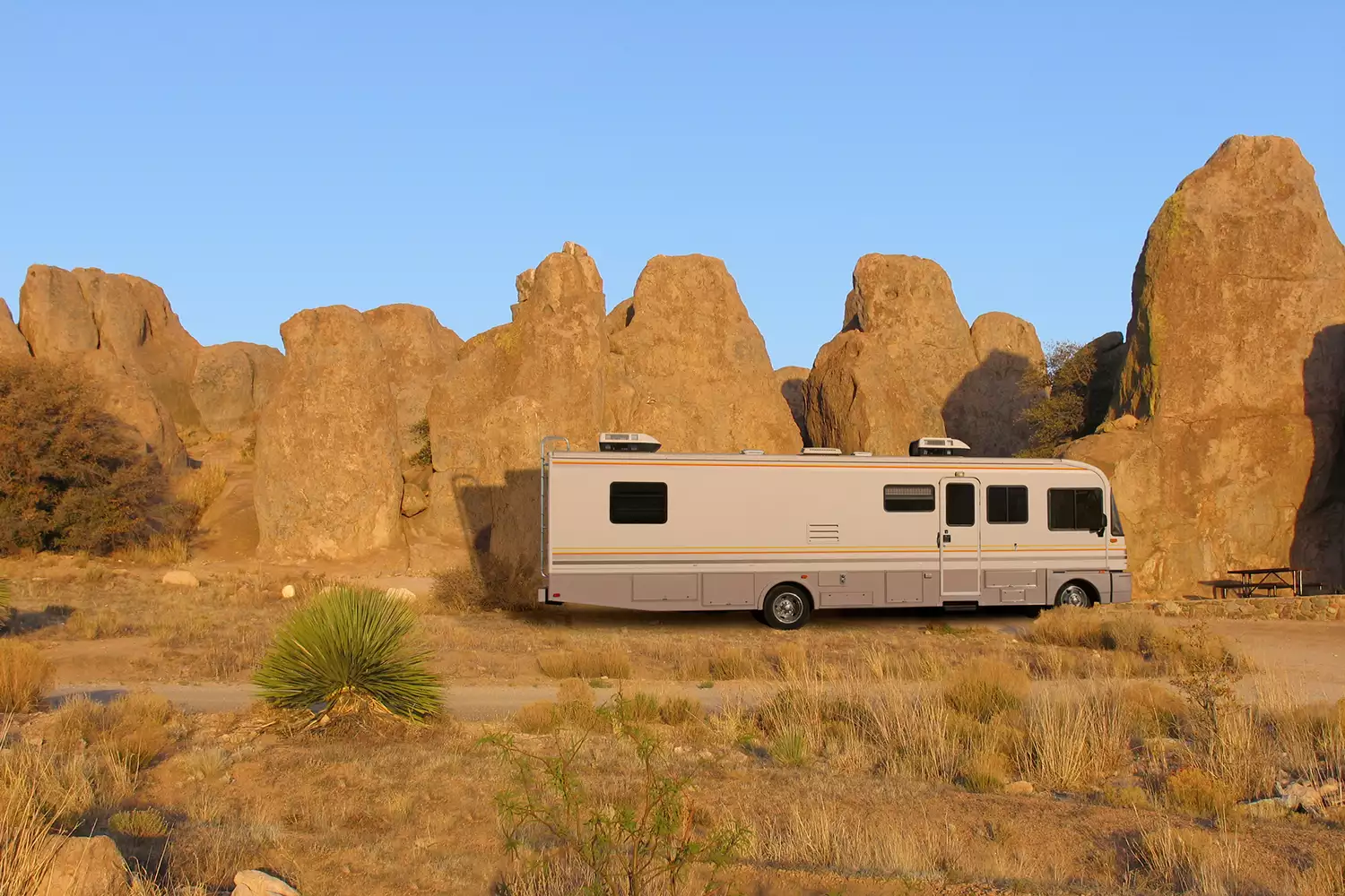A class motorhome parked at a designated campsite with hookups at City of Rocks State Park, New Mexico.