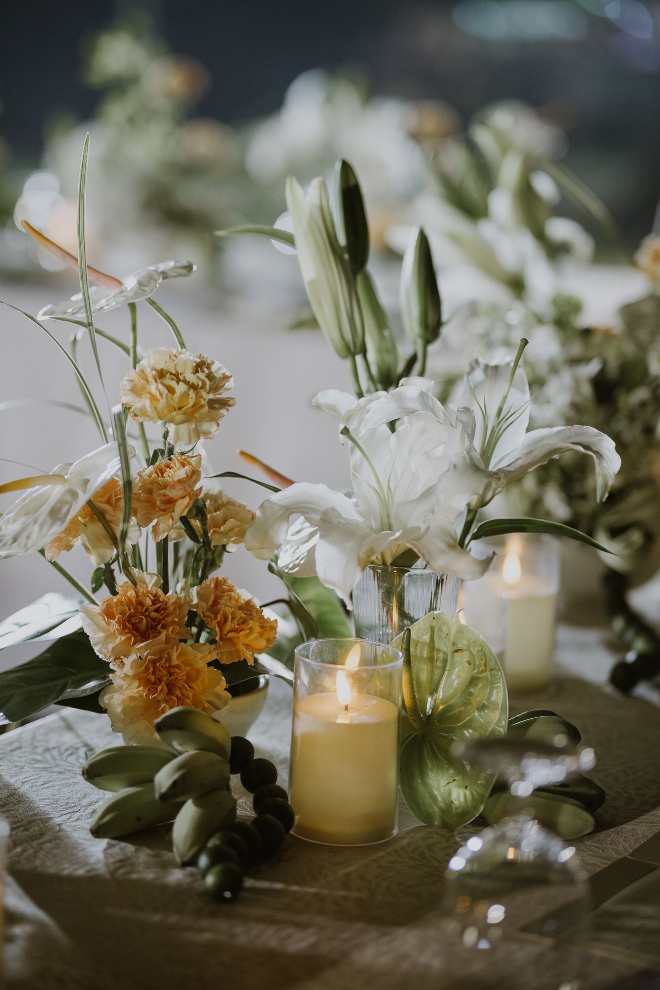 A close-up of a botanical minimalist wedding table setting featuring candles and lush greenery.