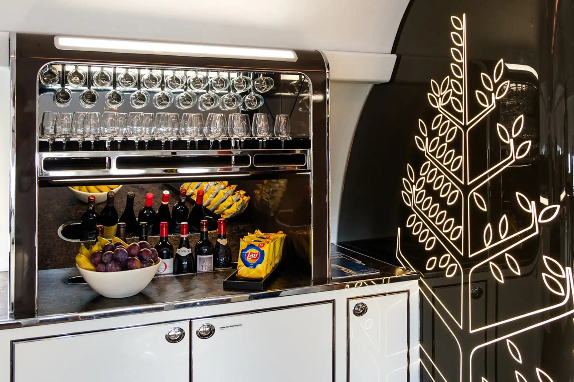 A close-up of the onboard refreshments bar featuring wine, fresh fruit, and elegant glassware.