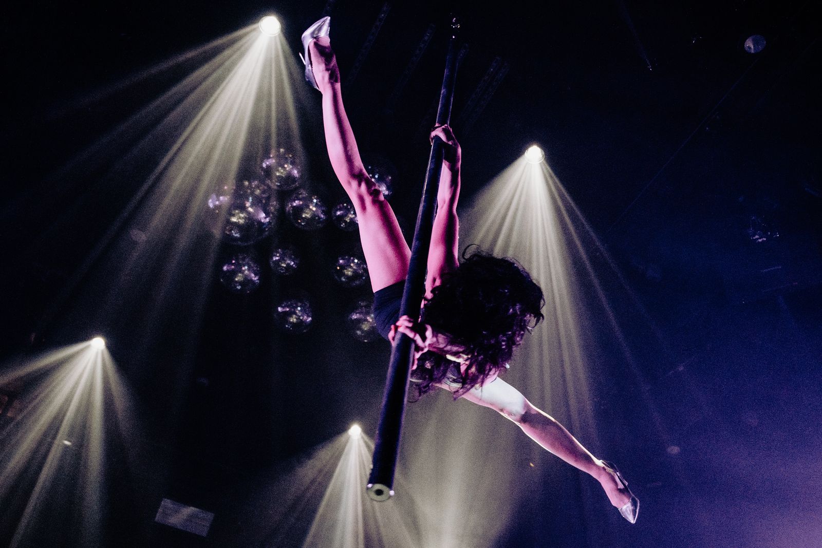 A stage performer in a sparkling costume performing a dance routine under dramatic stage lights.