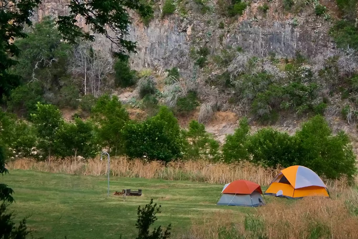 Two tents set up on a cliffside overlooking the wilderness at Colorado Bend State Park in Texas.