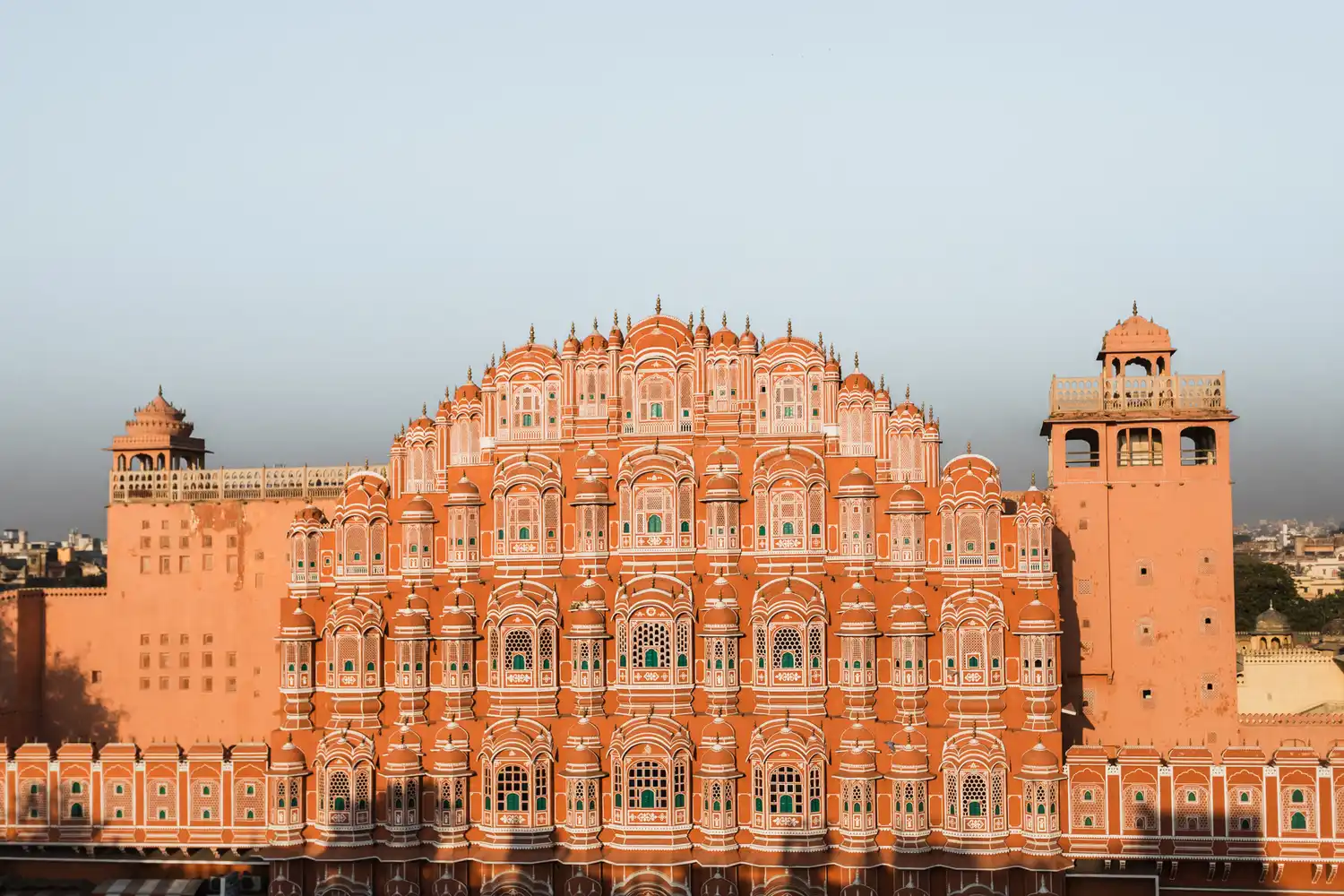 The red and pink sandstone facade of the Hawa Mahal palace with its numerous small windows.