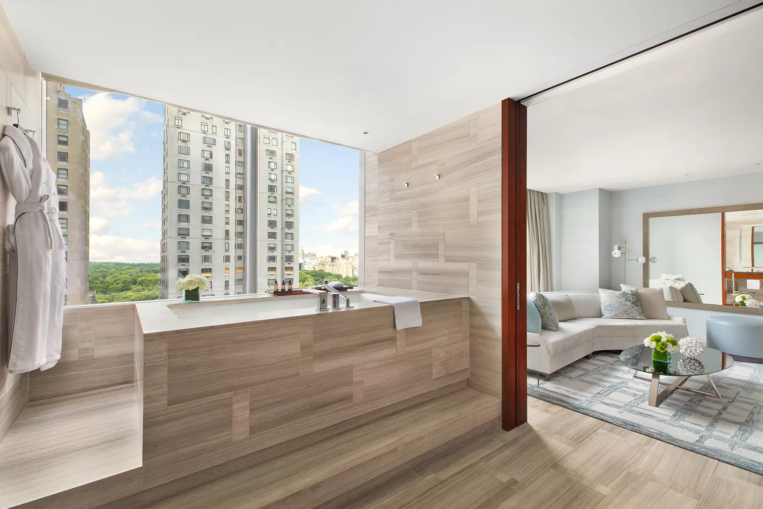 A luxury bathroom with a soaking tub positioned next to floor-to-ceiling windows overlooking Manhattan.