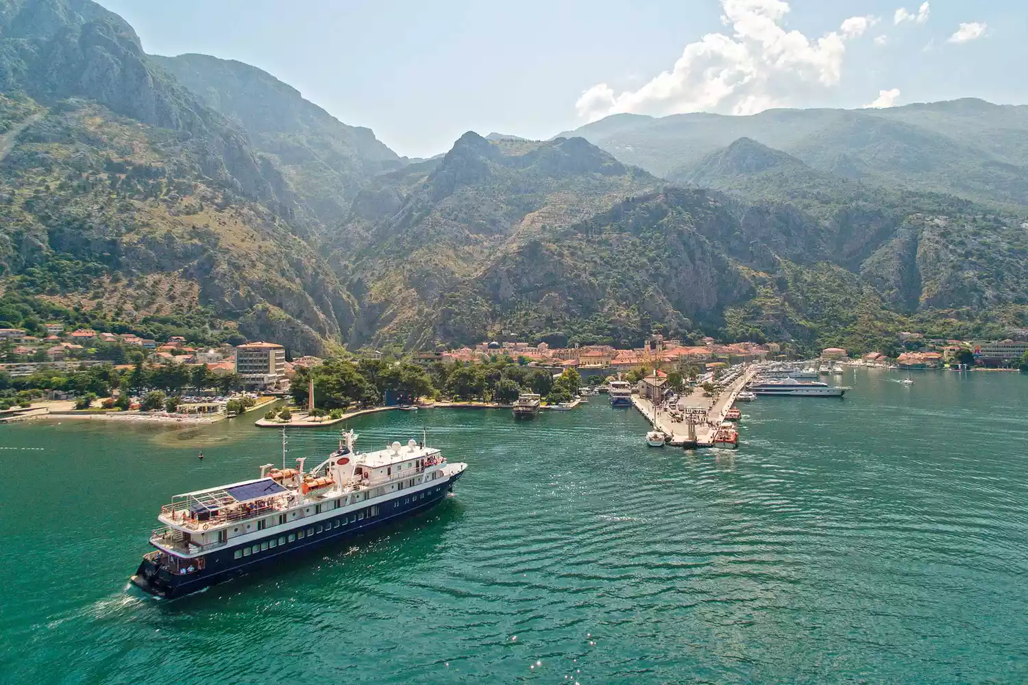 An Overseas Adventure Travel ship docked close to a small coastal town.