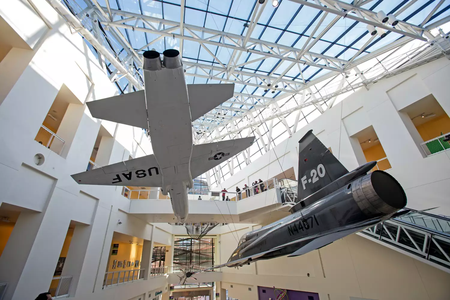 Visitors looking up at aerospace exhibits and planes inside the California Science Center.