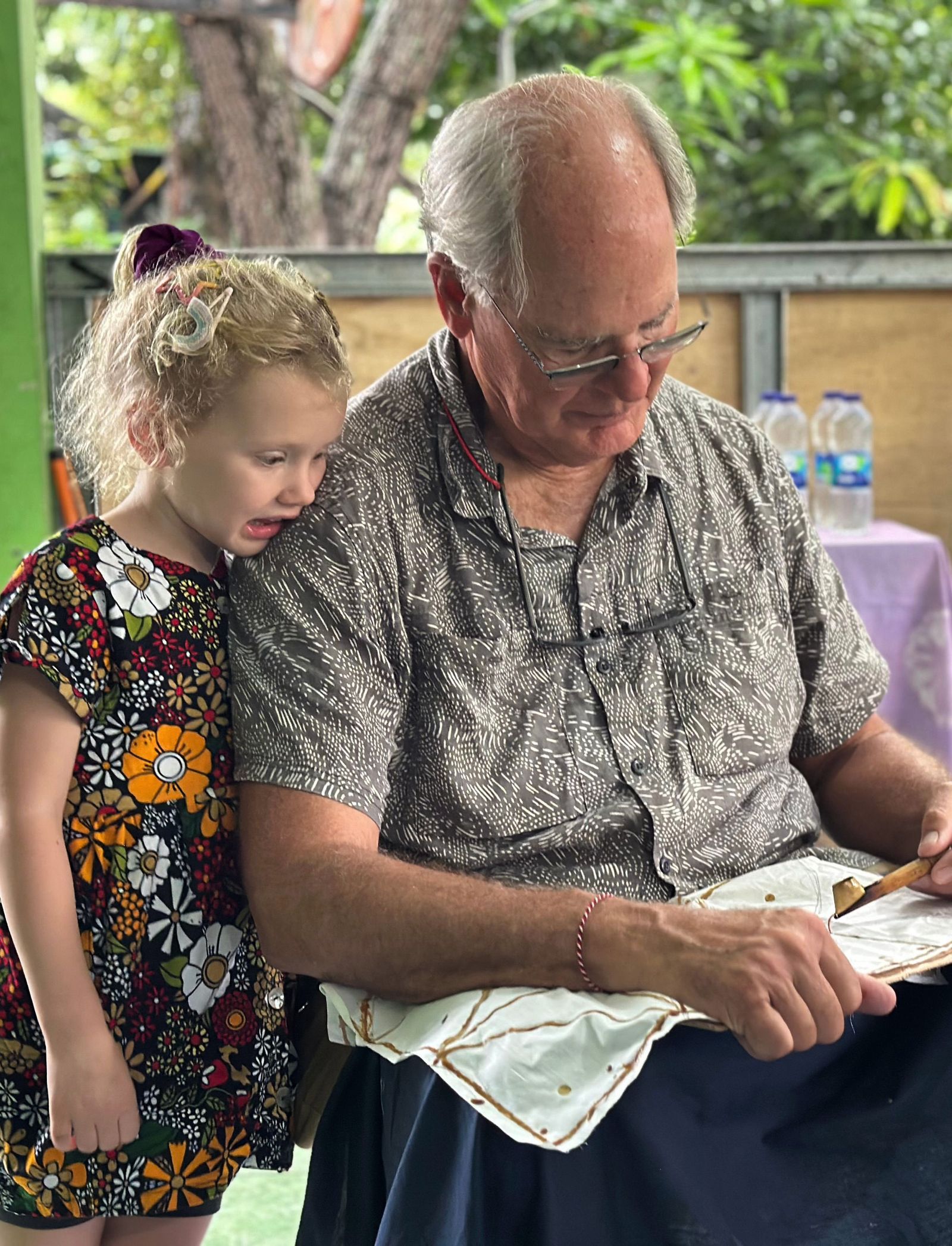 An adult and child focused on a traditional craft activity.