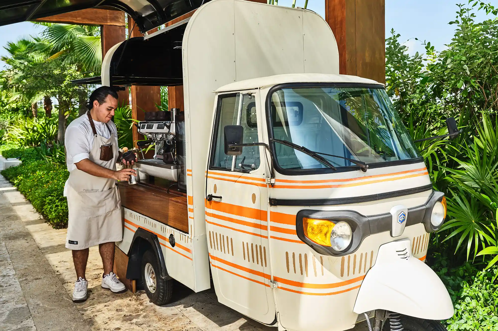 A personal attendant preparing a beverage at a luxury outdoor coffee cart.