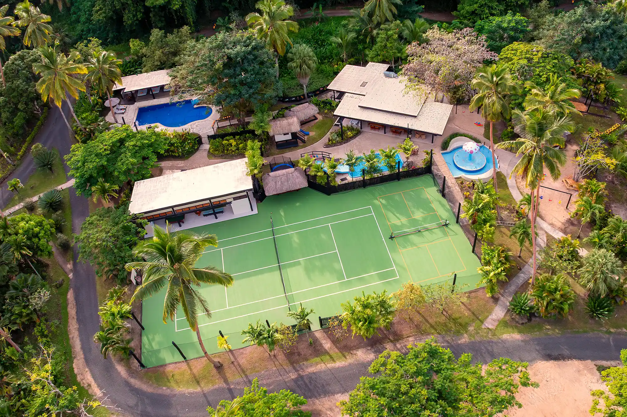 Aerial view of the Jean-Michel Cousteau Resort grounds including the pool, tennis court, and surrounding tropical foliage.
