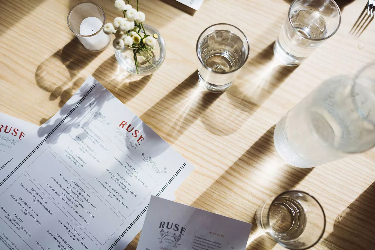 Table setting at Ruse restaurant with a dinner menu and wine glasses, reflecting an upscale dining atmosphere.