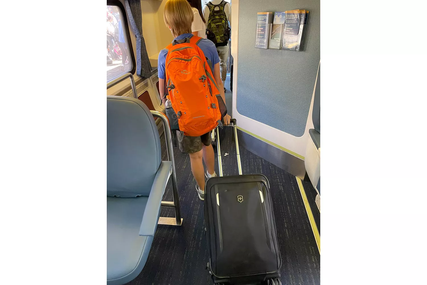 A young traveler with a suitcase boarding the Amtrak Pacific Surfliner train.