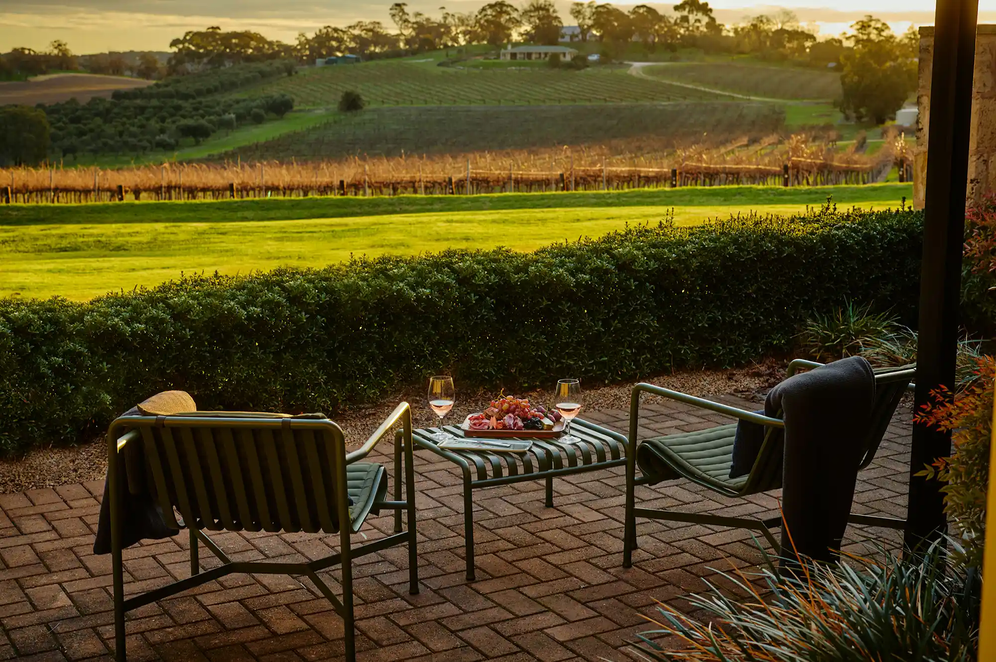 Two outdoor chairs and a table with refreshments overlooking a sunny landscape.