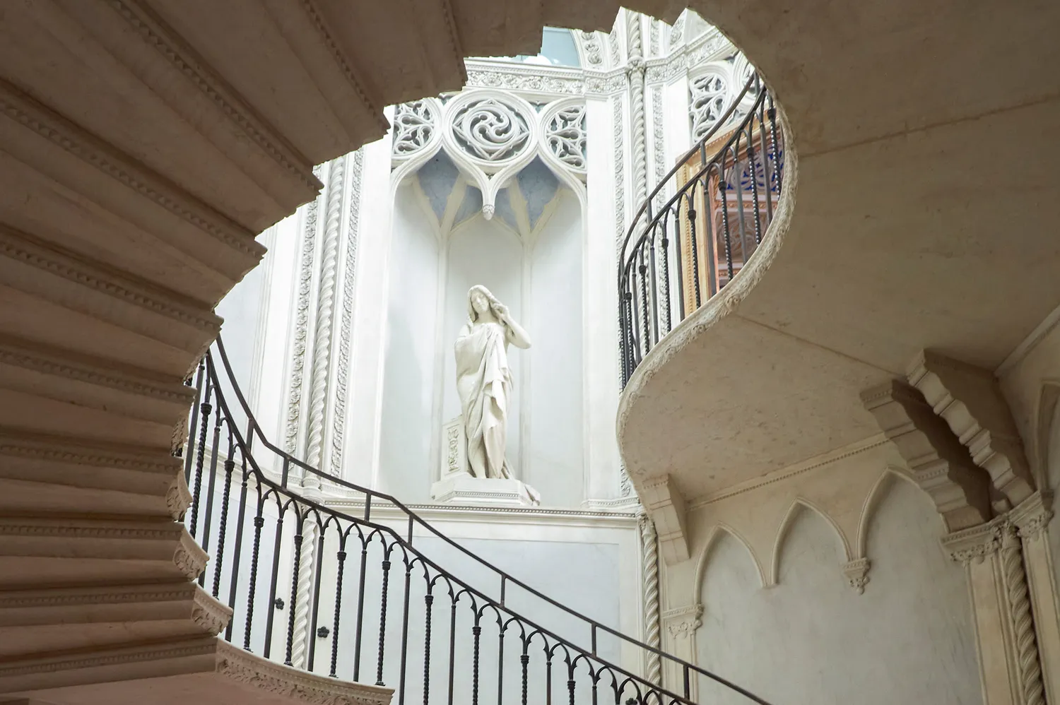 An ornate staircase with a central statue reflecting Venetian Late Gothic architecture.