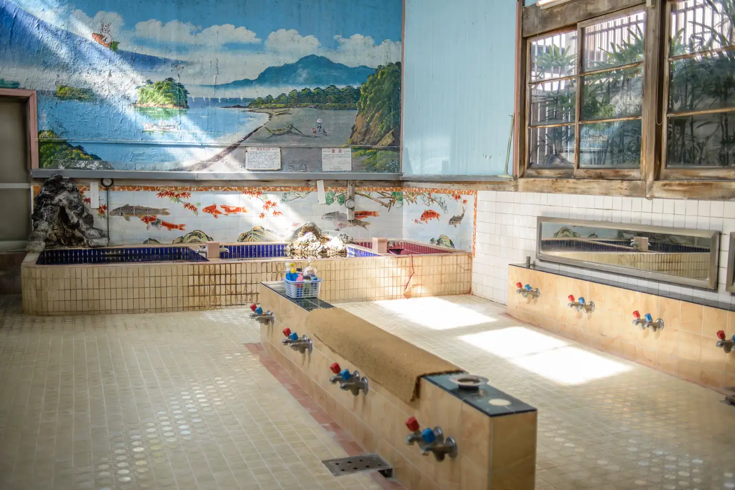 Interior of a traditional Japanese sento public bath with ornate tile work and mountain murals.